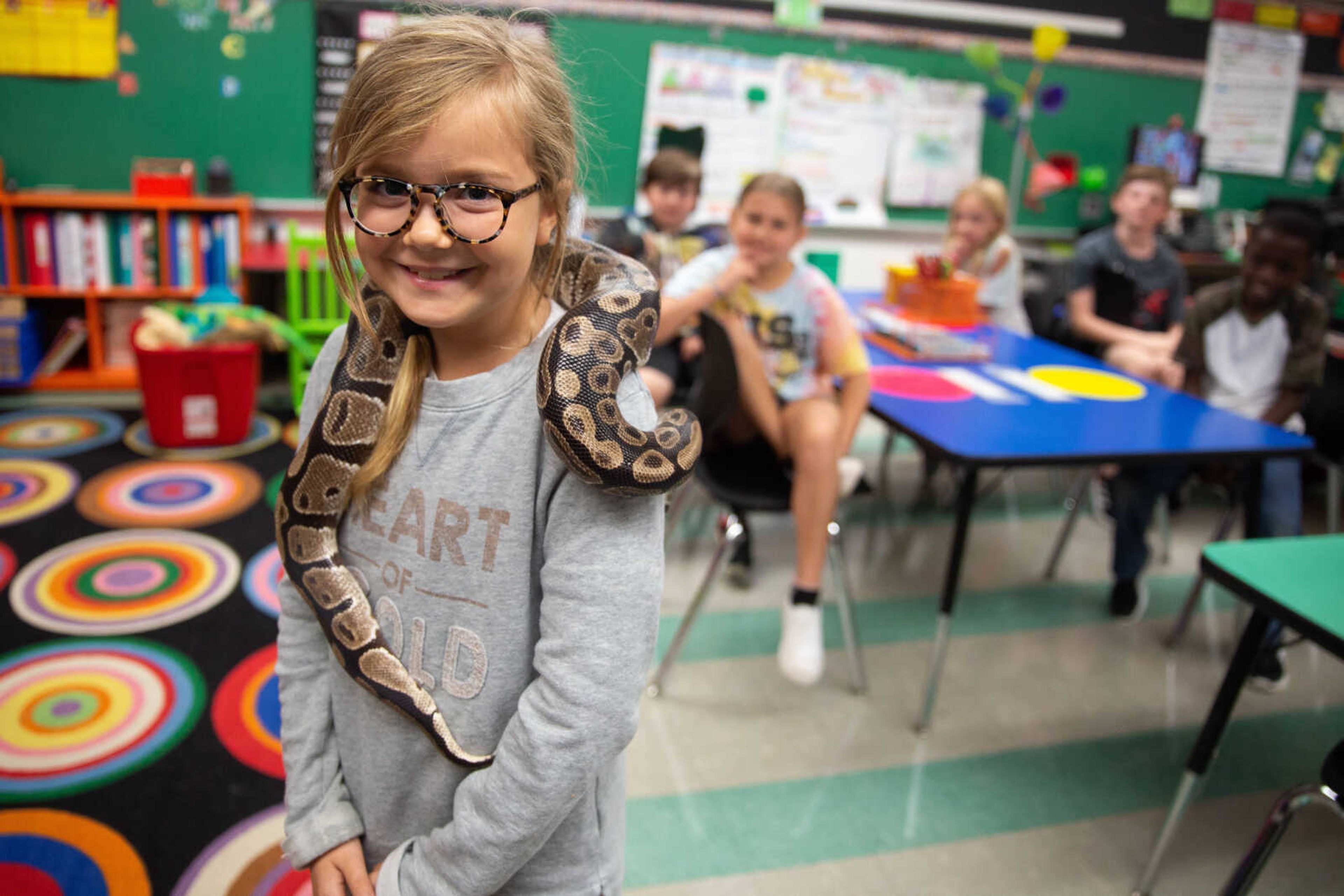 Olive Bourisaw stands in Mrs. Young's fourth grade classroom as Monty the snake wraps himself around her.