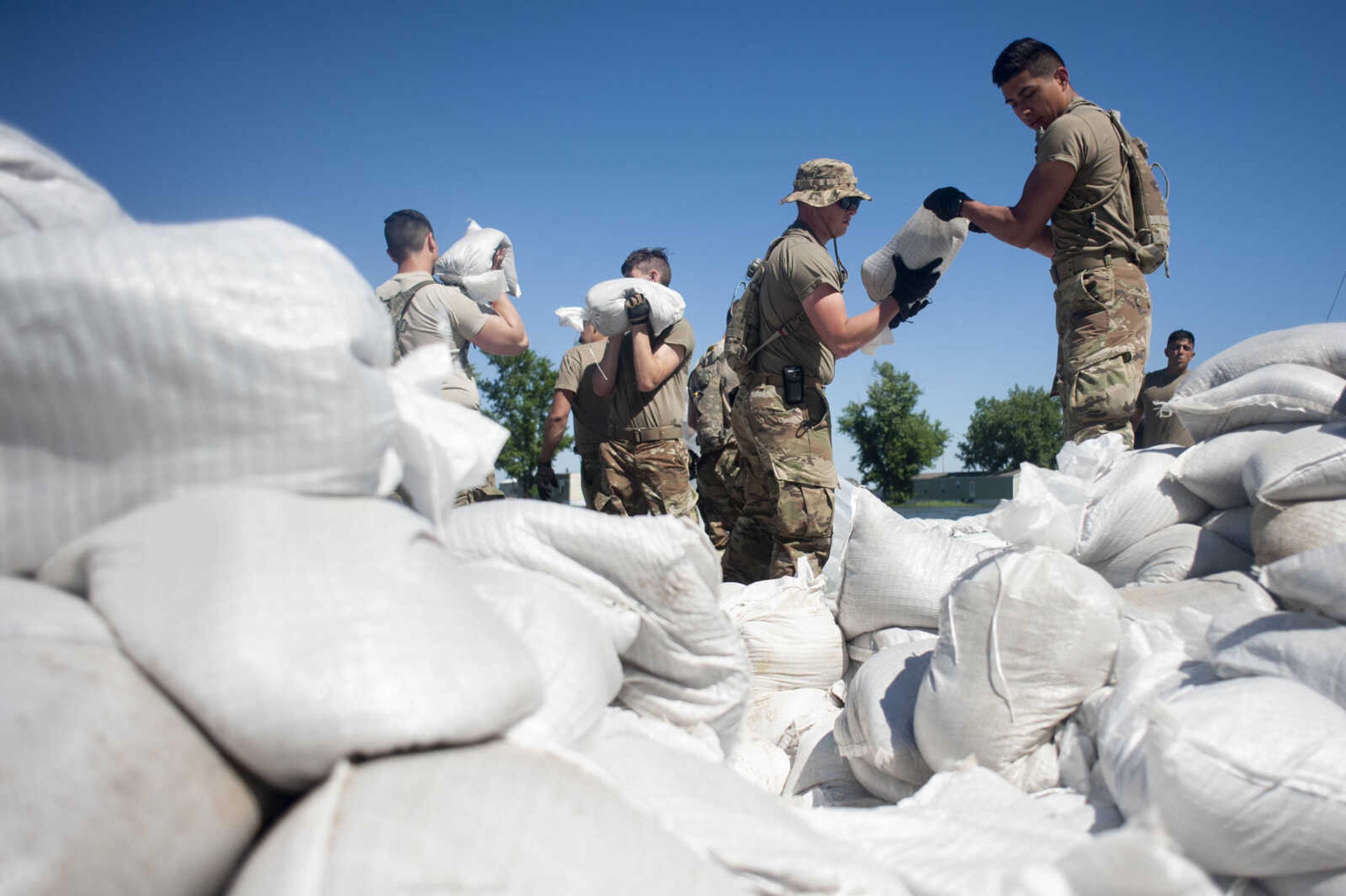 Illinois National Guard member Alex Escobar, right, and fellow Guard member Michael Sheppard help build up existing sandbag barriers to hold back floodwaters Monday, June 10, 2019, along Brookwood Drive in East Cape Girardeau, Illinois.