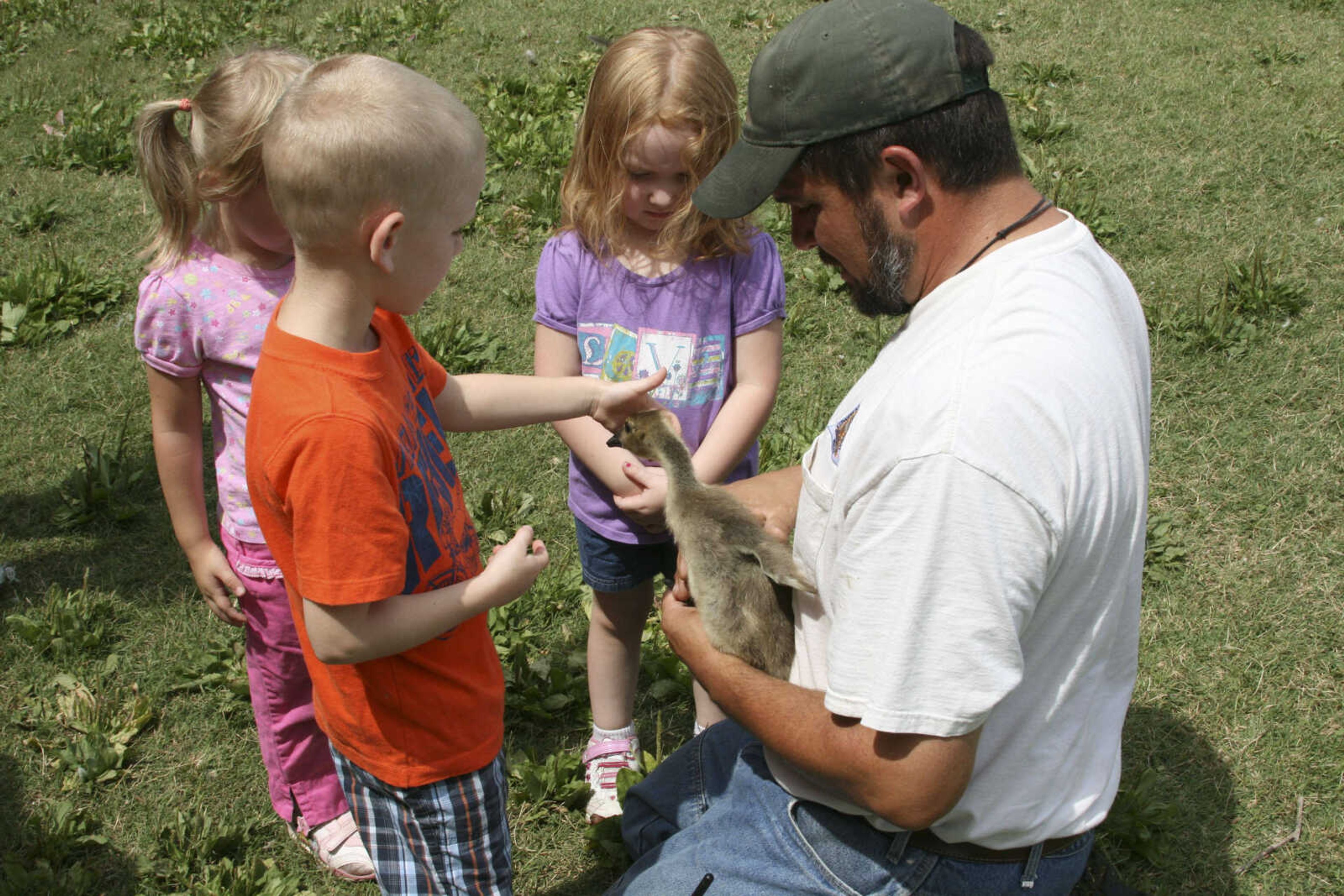 Wildlife Management Biologist Matt Bowyer holds a gosling for children to view at Capaha Park in Cape Girardeau. (Missouri Department of Conservation photo by AJ Hendershott)