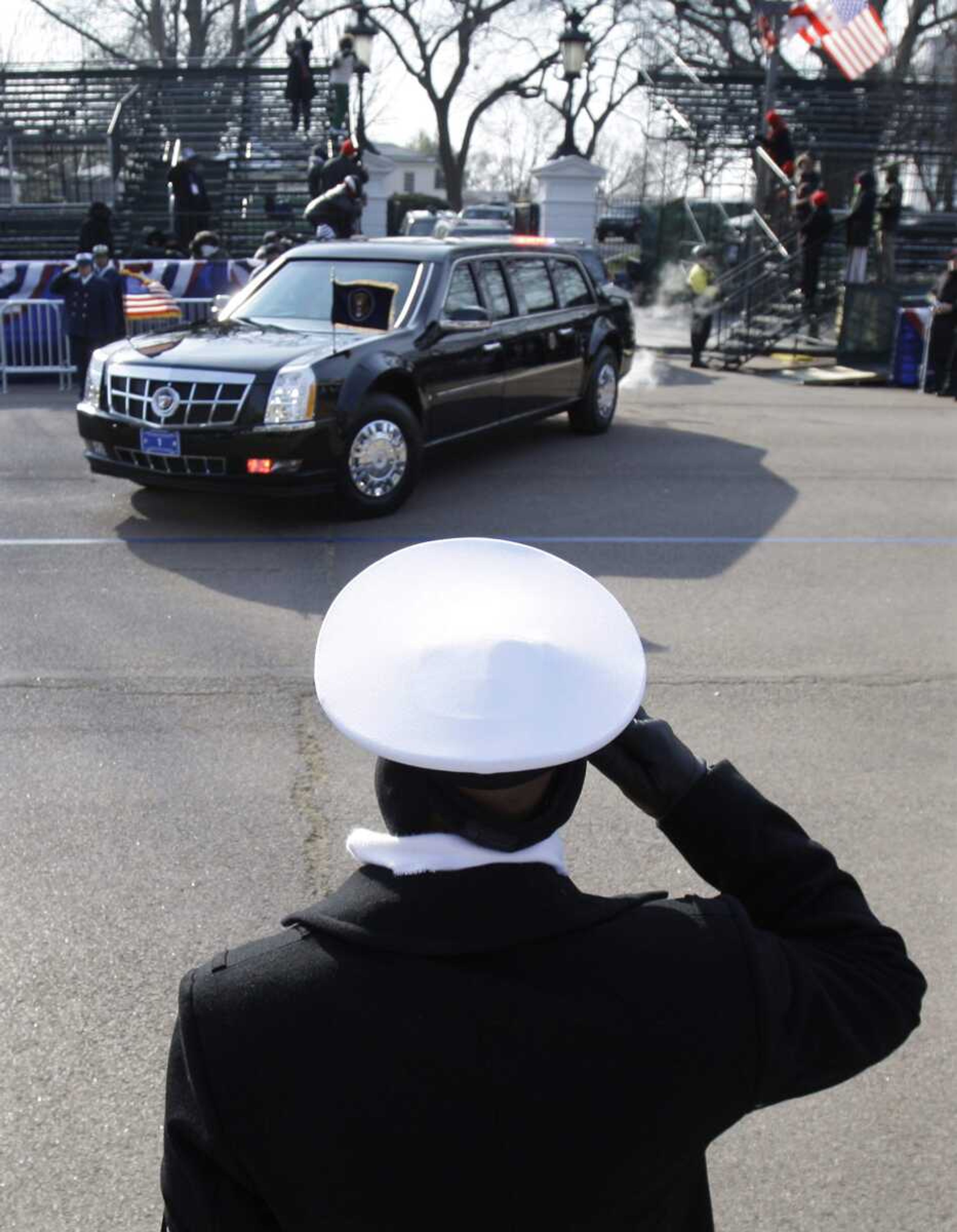 A sailor salutes as the limousine carrying President George W. Bush and President-elect Barack Obama leave the White House in Washington, Tuesday, Jan. 20, 2009. (AP Photo/Charlie Neibergall)