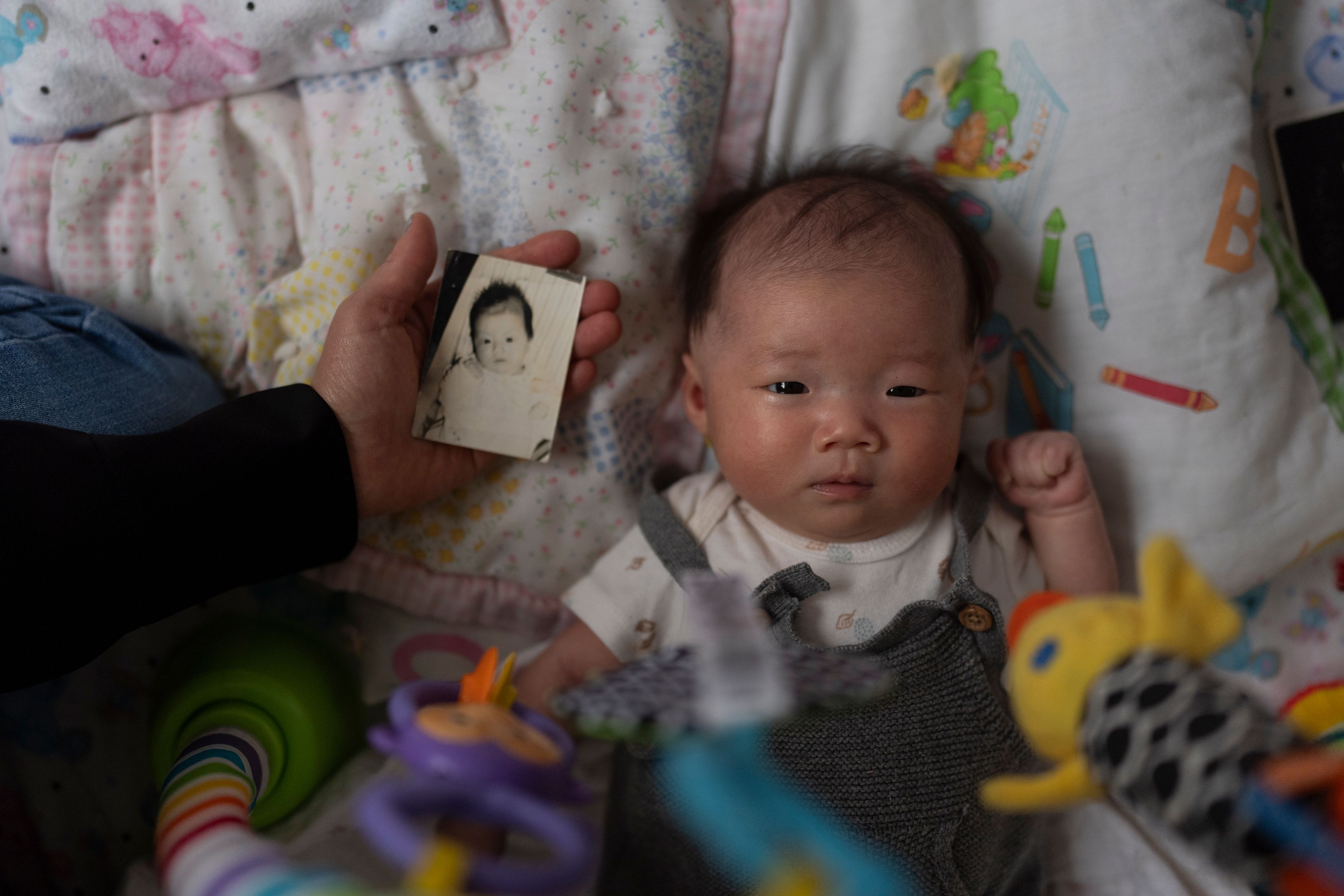 Michaela Dietz, an adoptee from South Korea, holds a baby photo of Robyn Joy Park, who was also adopted from South Korea as an infant and whose identity was switched, next to Park's newborn daughter, Rae, while visiting Park at her home in Pasadena, Calif., Friday, April 19, 2024. Park hasn't found her real parents. She thinks often of the girl whose identity she was given, and wonders: what happened to her? (AP Photo/Jae C. Hong)