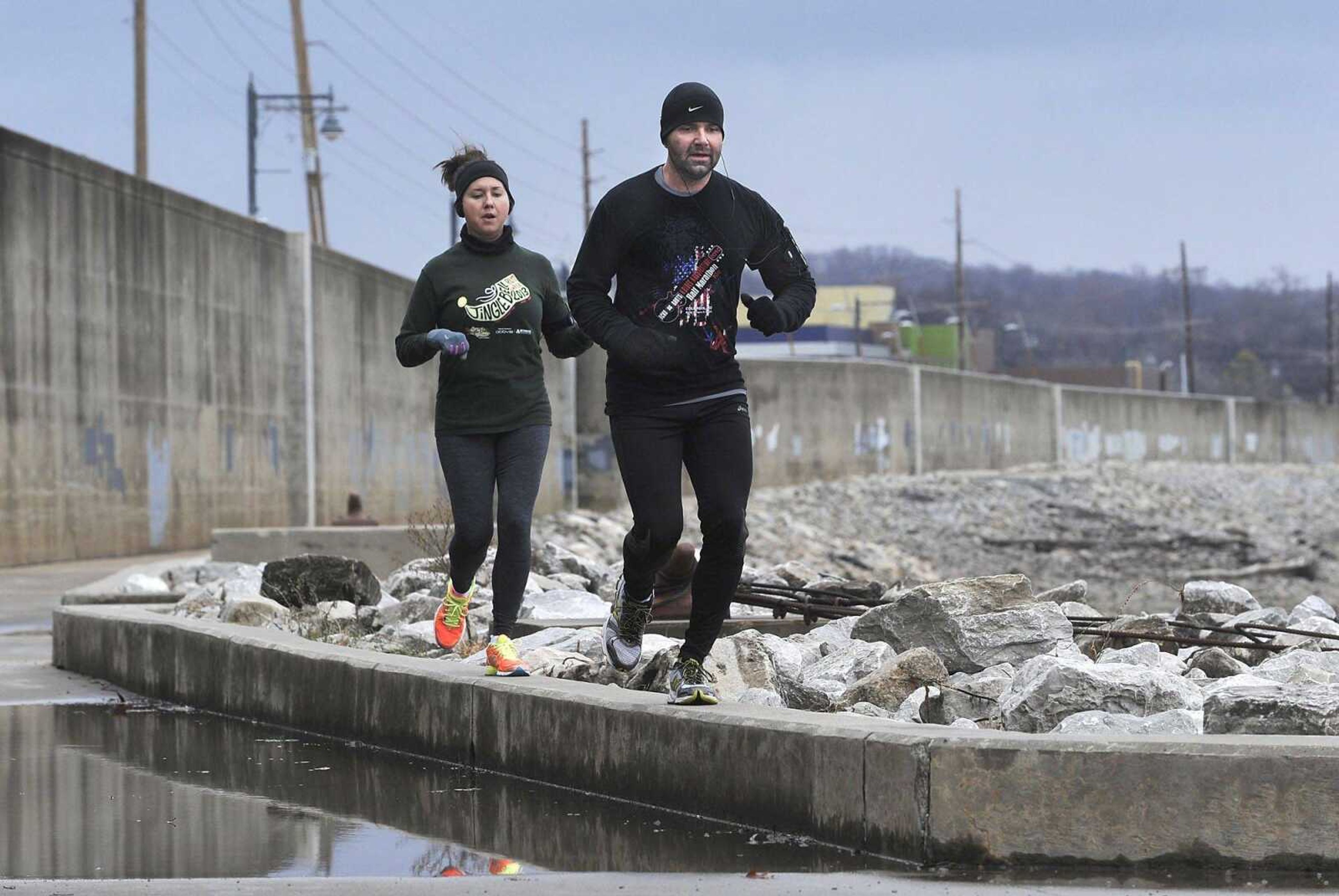 Brendt Cyr leads the way for Casey Cyr of Jackson while taking their morning run to the next level, avoiding a puddle covering the Mississippi River Walk trail, on Sunday in downtown Cape Girardeau. It was 42 degrees, and temperatures fell below freezing by midafternoon. The trail is scheduled to be extended this year approximately 300 feet north to the Department of Conservation's Red Star Access. The project will include a 10-foot-wide pedestrian bridge over Sloan's Creek. The trail will also be extended south approximately 1,600 feet along the floodwall. (Fred Lynch)