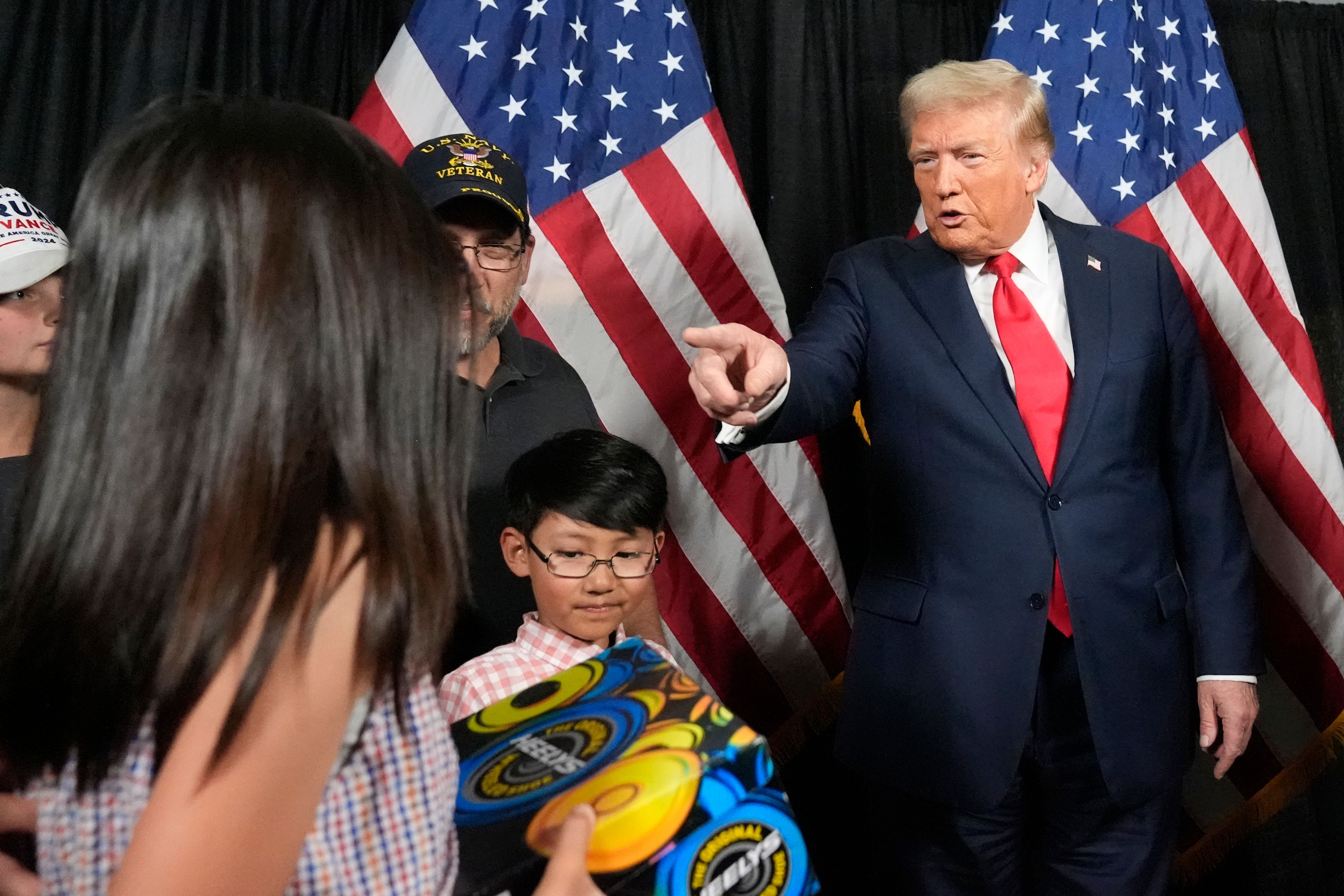 Republican presidential nominee former President Donald Trump, right, gifts a young attendee a pair of shoes before he speaks at a campaign rally at the Calhoun Ranch, Saturday, Oct. 12, 2024, in Coachella, Calif. (AP Photo/Alex Brandon)