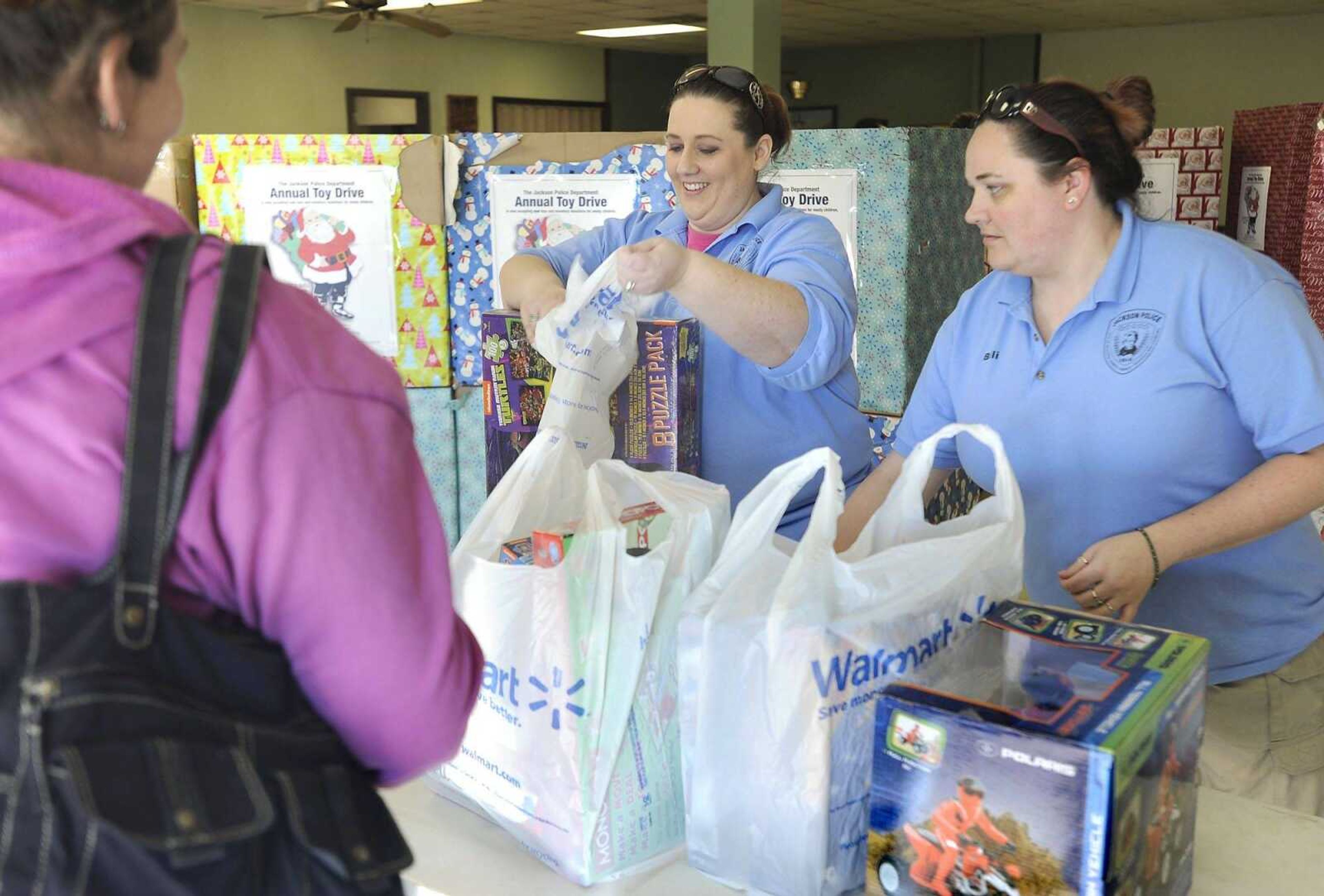 Rachel Coleman and Billi Knight, right, with the Jackson Police Department gather  toys collected from their annual toy drive for Tabatha Bain, who picked them up Friday at the Jackson Elks Lodge. (Fred Lynch)