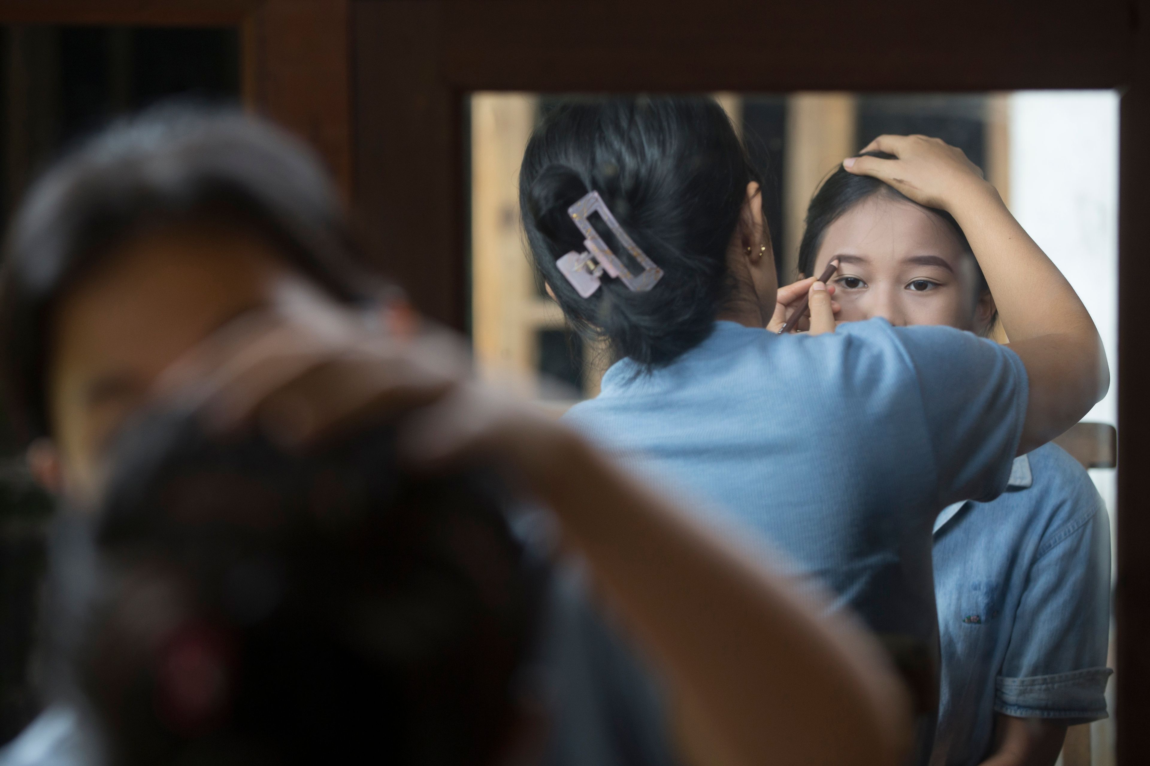 Intan Wahyuni applies makeup for her younger sister Ketut Nita Wahyuni, 11, before participating in Rejang Pucuk Hindu rituals at Geriana Kauh village, Karangasem, Bali, Indonesia on Thursday, Nov. 21, 2024. (AP Photo/Firdia Lisnawati)