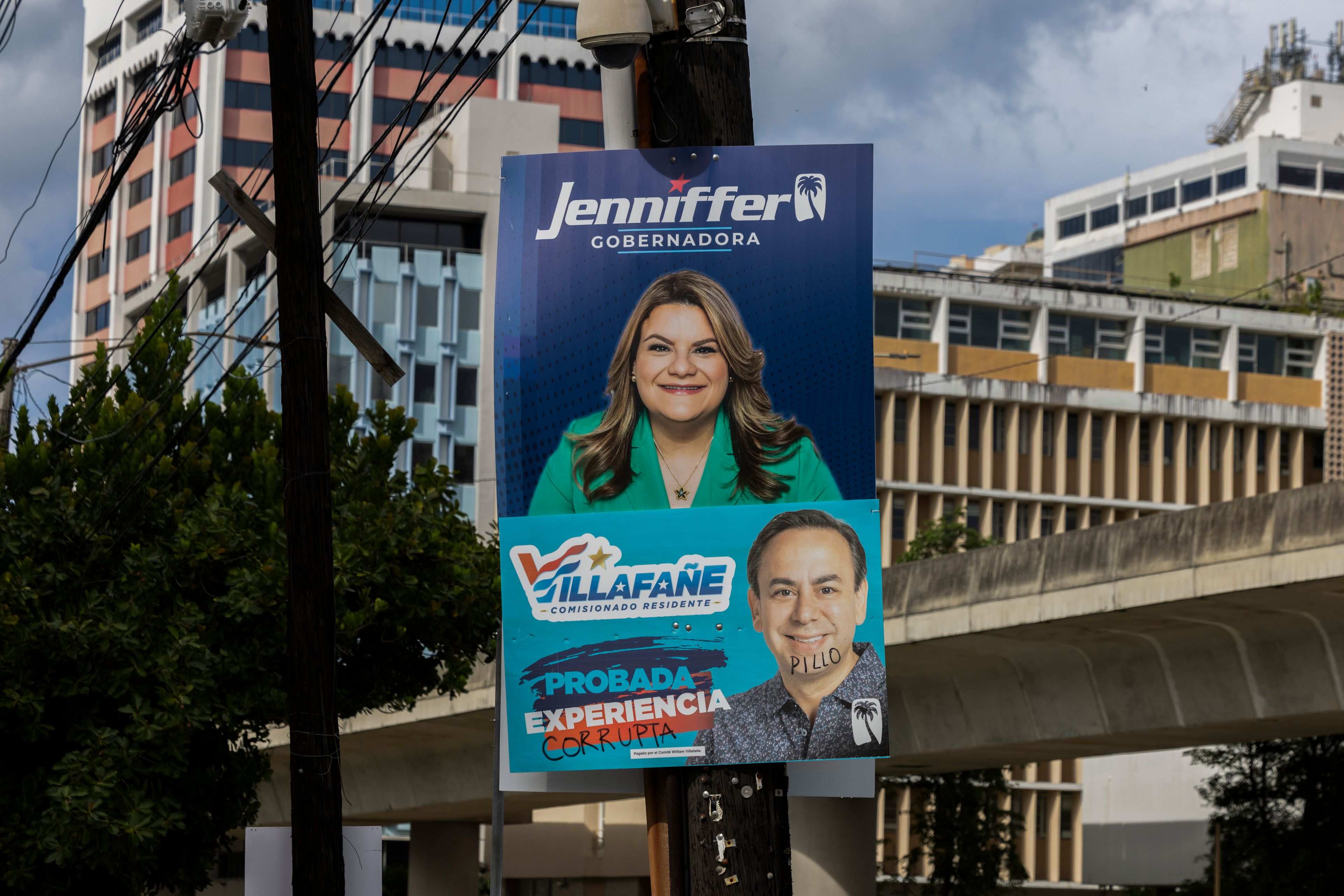 A campaign poster promotes New Progressive Party gubernatorial candidate and Puerto Rico’s representative in Congress Jenniffer González, above a campaign poster of resident commissioner candidate Luis Villafañe, defaced with the Spanish words for corrupt and rogue, in San Juan, Puerto Rico, Saturday, Nov. 2, 2024. (AP Photo/Alejandro Granadillo)