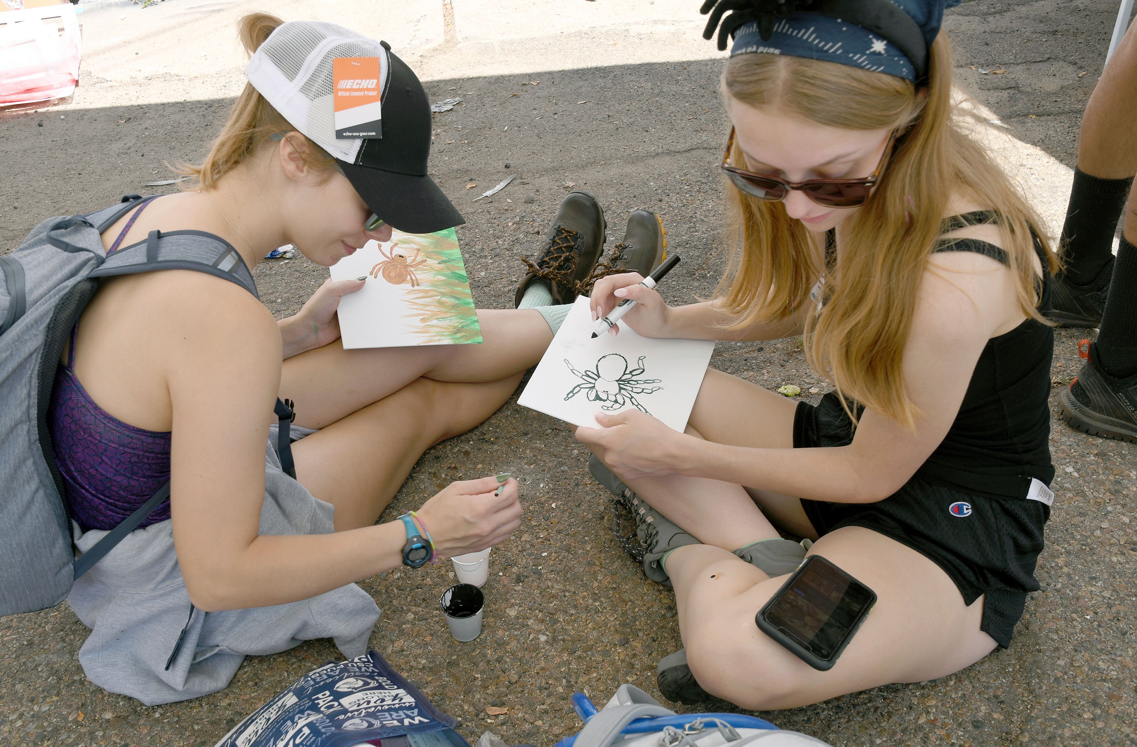 Kendall Foreman, left, and Raven Myhre, right, both of Fort Collins, Colo., create artwork at the Tarantula Festival in La Junta, Colo., on Saturday, Sept. 28, 2024. (AP Photo/Thomas Peipert)