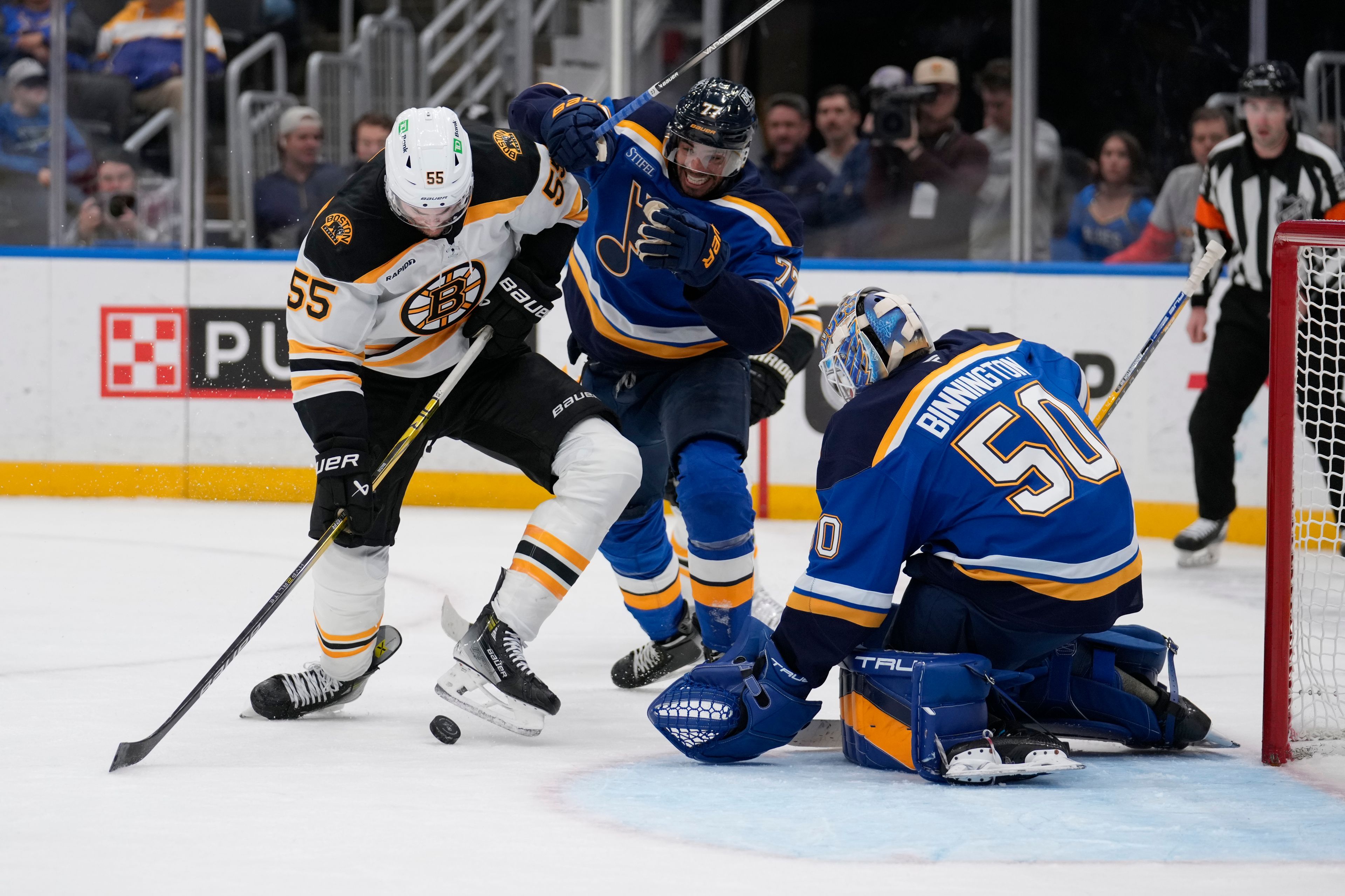 Boston Bruins' Justin Brazeau (55) looks at the puck as St. Louis Blues goaltender Jordan Binnington (50) and Pierre-Olivier Joseph (77) defend during the third period of an NHL hockey game Tuesday, Nov. 12, 2024, in St. Louis. (AP Photo/Jeff Roberson)