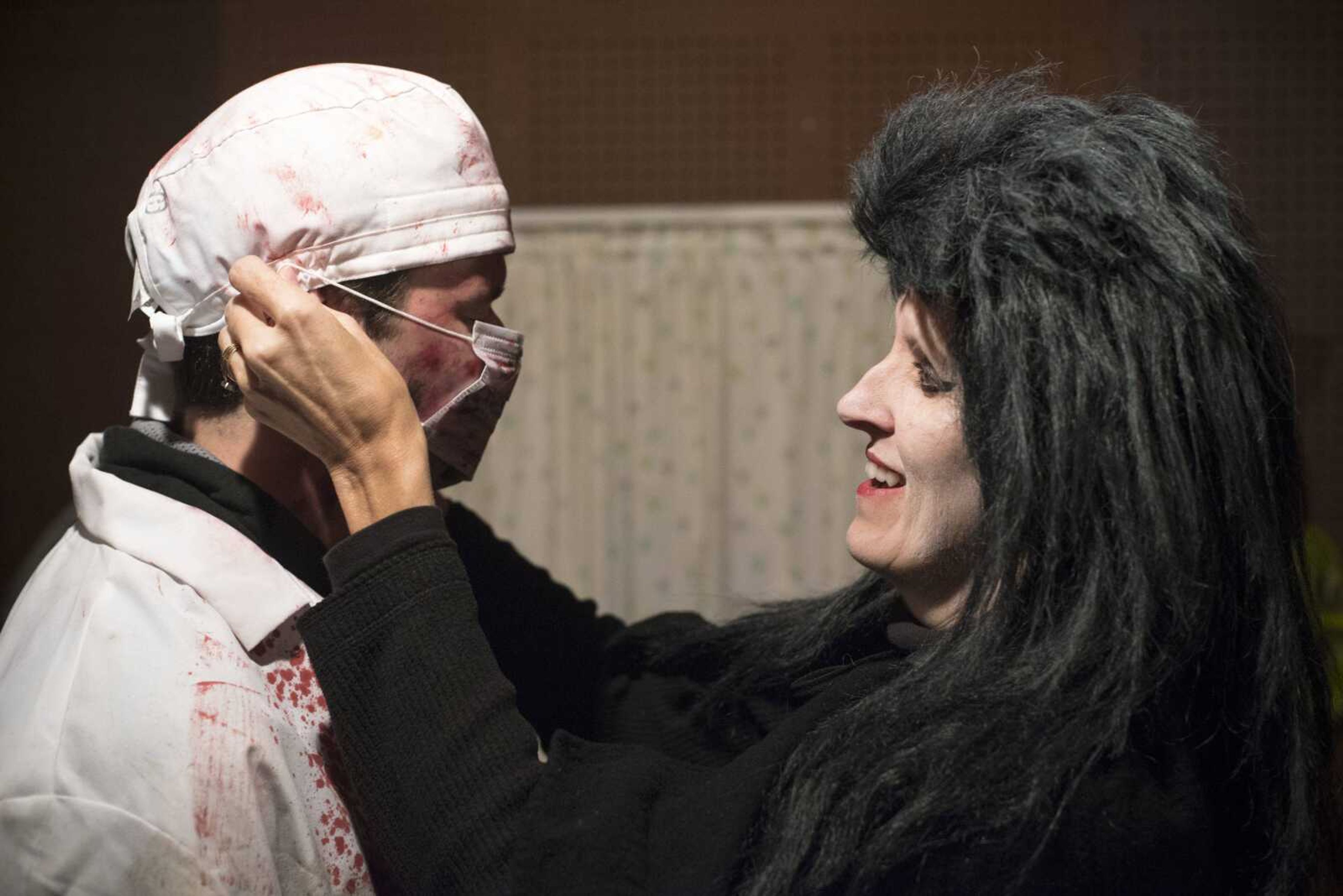 Gate attendant Darla Macke, right, straps a doctor's mask onto her son, Cody, as he prepares to scare guests in a hospital scene Oct. 12, at Black Forest Haunted Ghost Town.