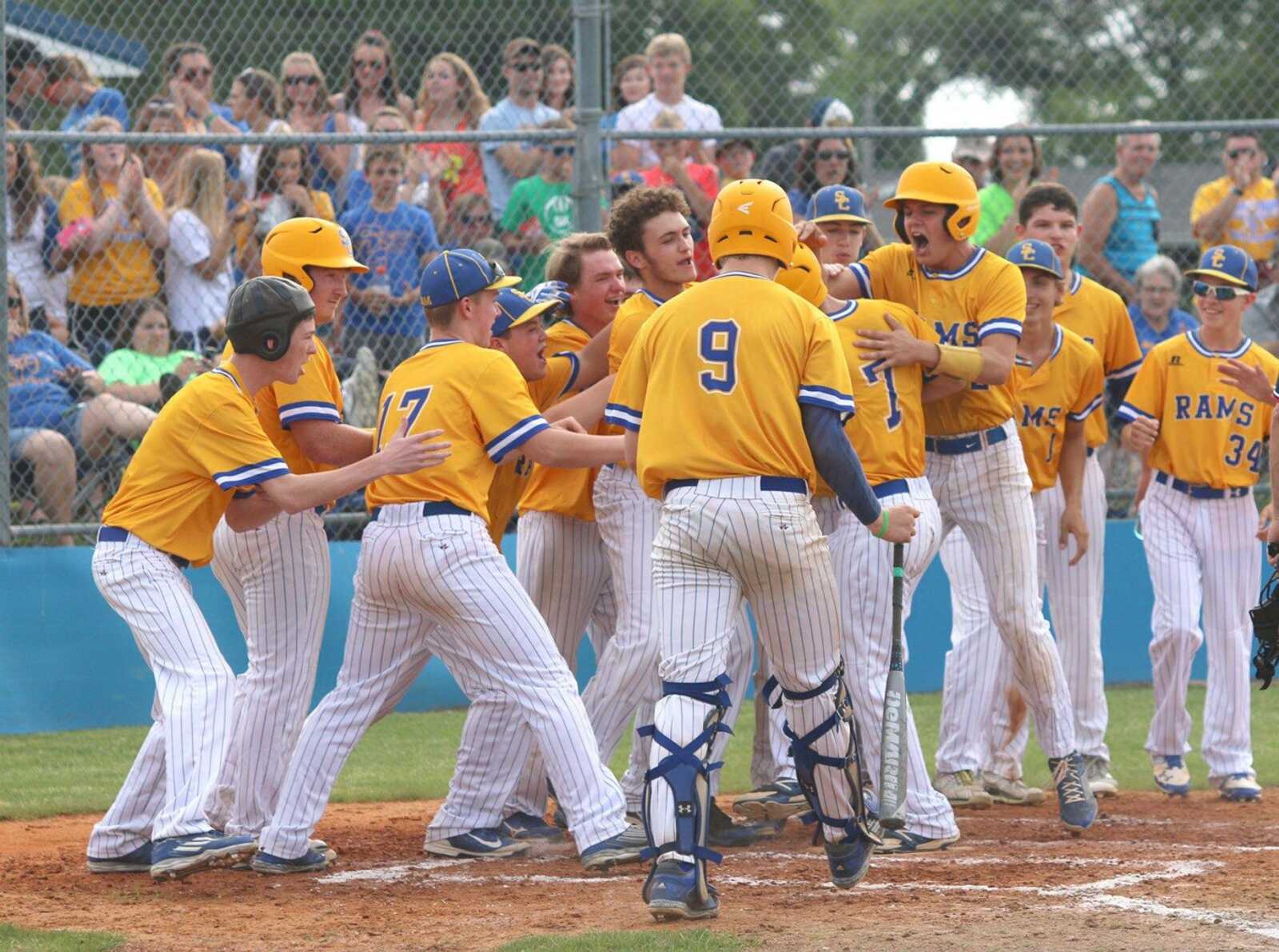 Scott City players greet Trent Pobst (7) at home plate after he hit a solo home run against New Madrid County Central during the third inning of a Class 3 Sectional in Scott City, Missouri.