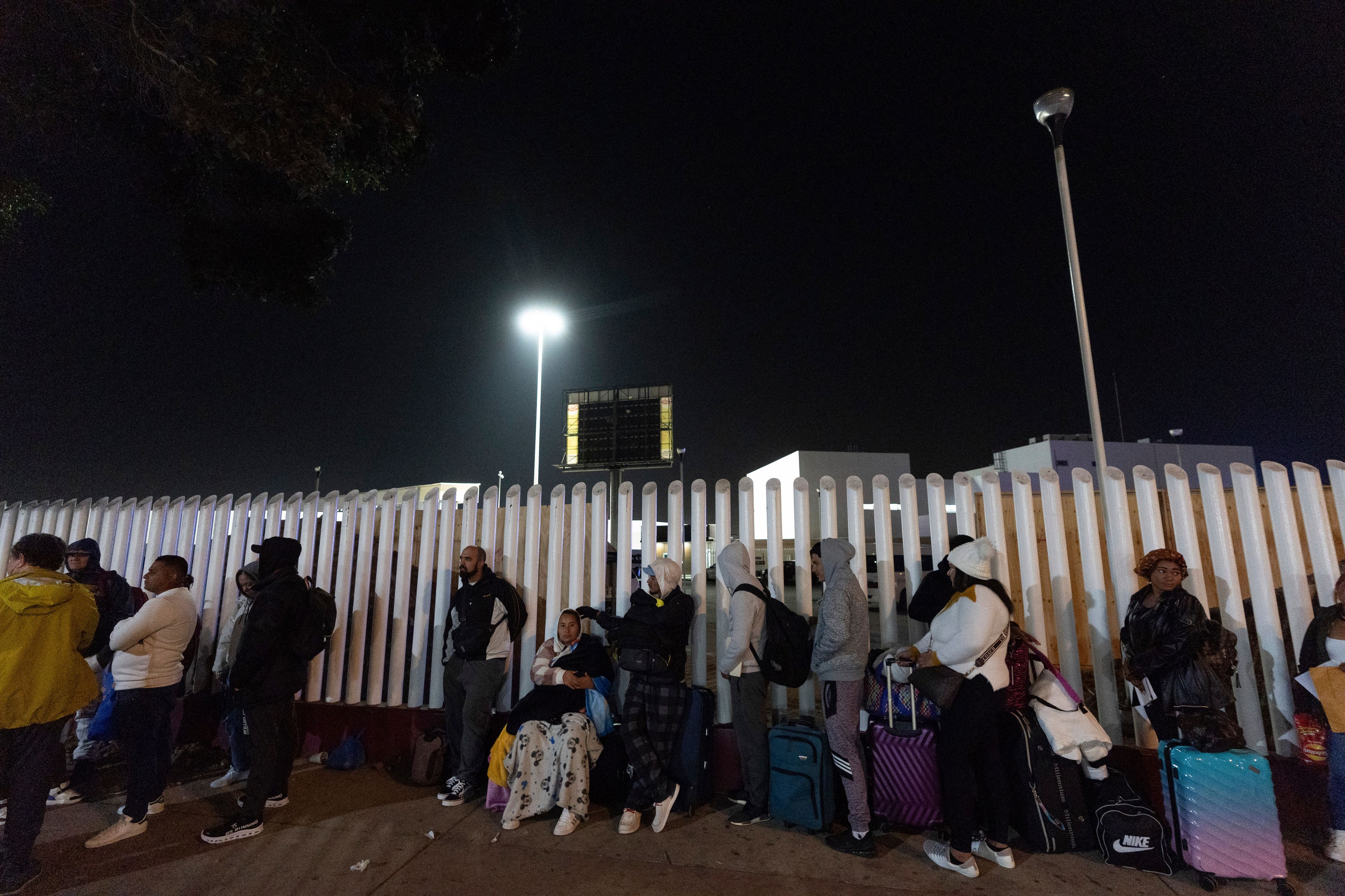 FILE - Migrants from Cuba and Venezuela line up at a Mexican immigration checkpoint as they make their way across the border for appointments to legally apply for asylum in the United States, on Nov. 5, 2024, in Tijuana, Mexico. (AP Photo/Gregory Bull, File)