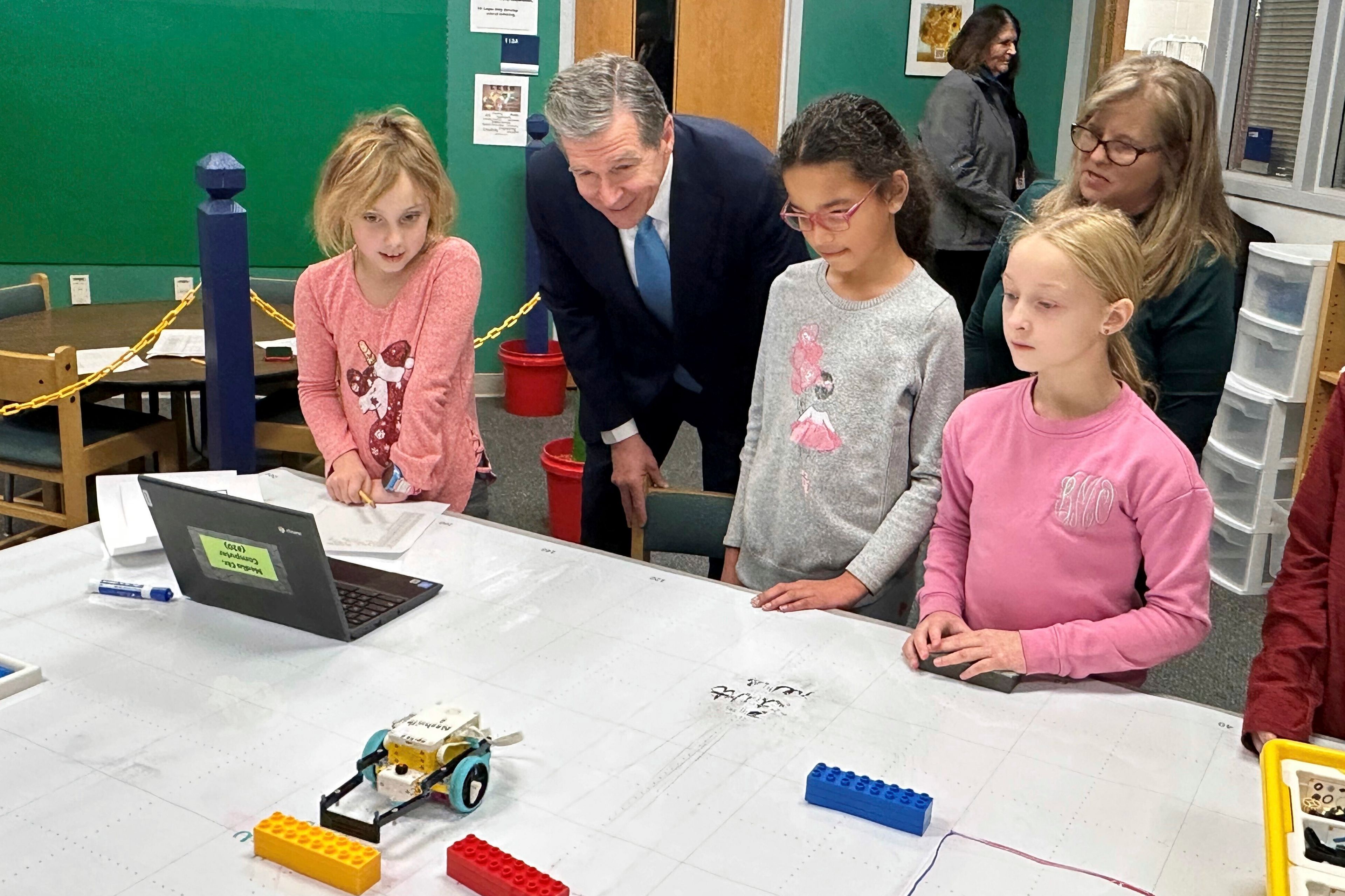 FILE - North Carolina Gov. Roy Cooper, center left, watches a robotics team at Nashville Elementary School in Nashville, N.C., direct its vehicle in the school library, Tuesday, Jan. 23, 2024. (AP Photo/Gary D. Robertson, File)