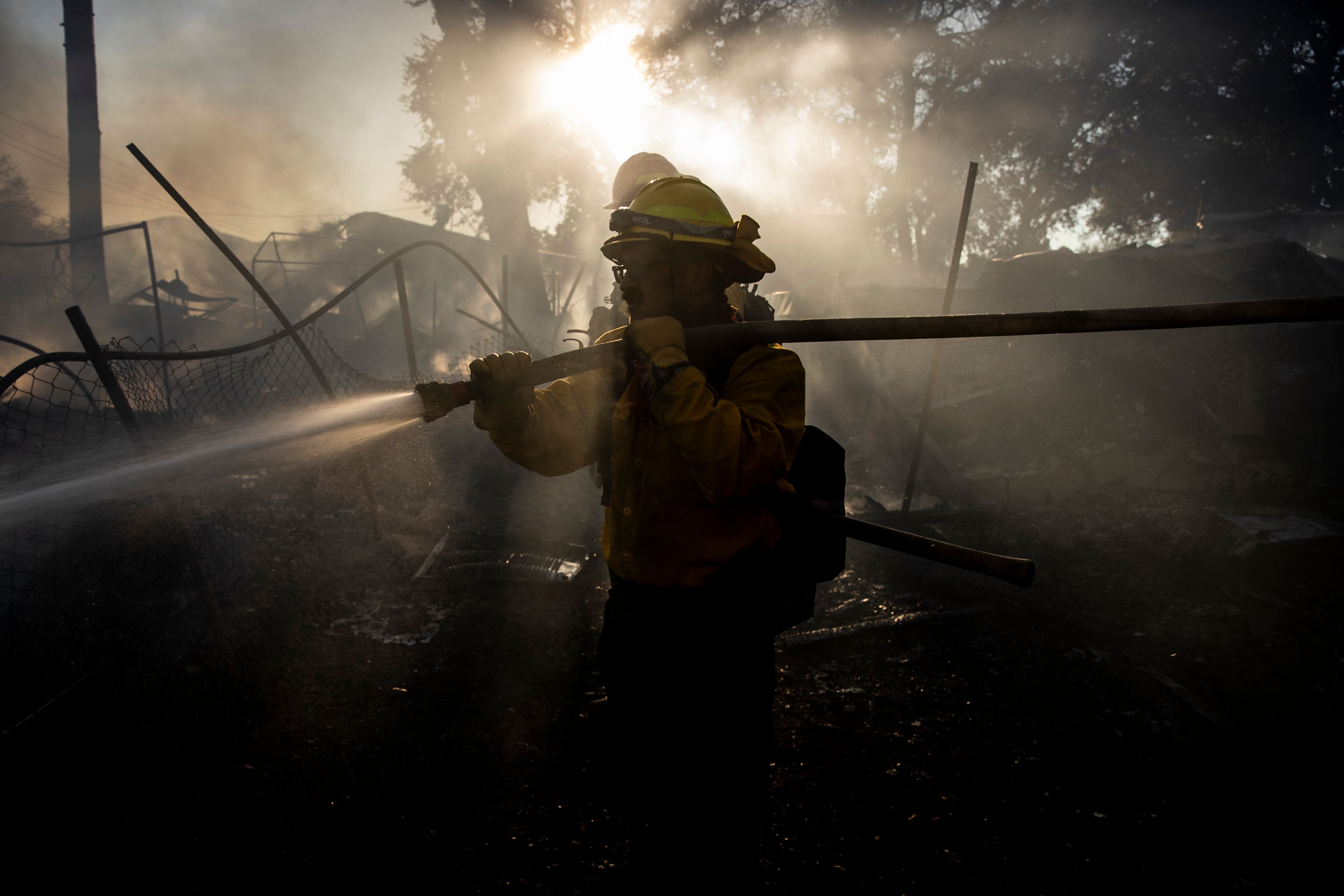 A contract firefighter from Colorado Springs, Colo., douses water on a damaged structure during the Boyles fire in Clearlake, Calif., Sunday, Sept. 8, 2024. (Stephen Lam/San Francisco Chronicle via AP)