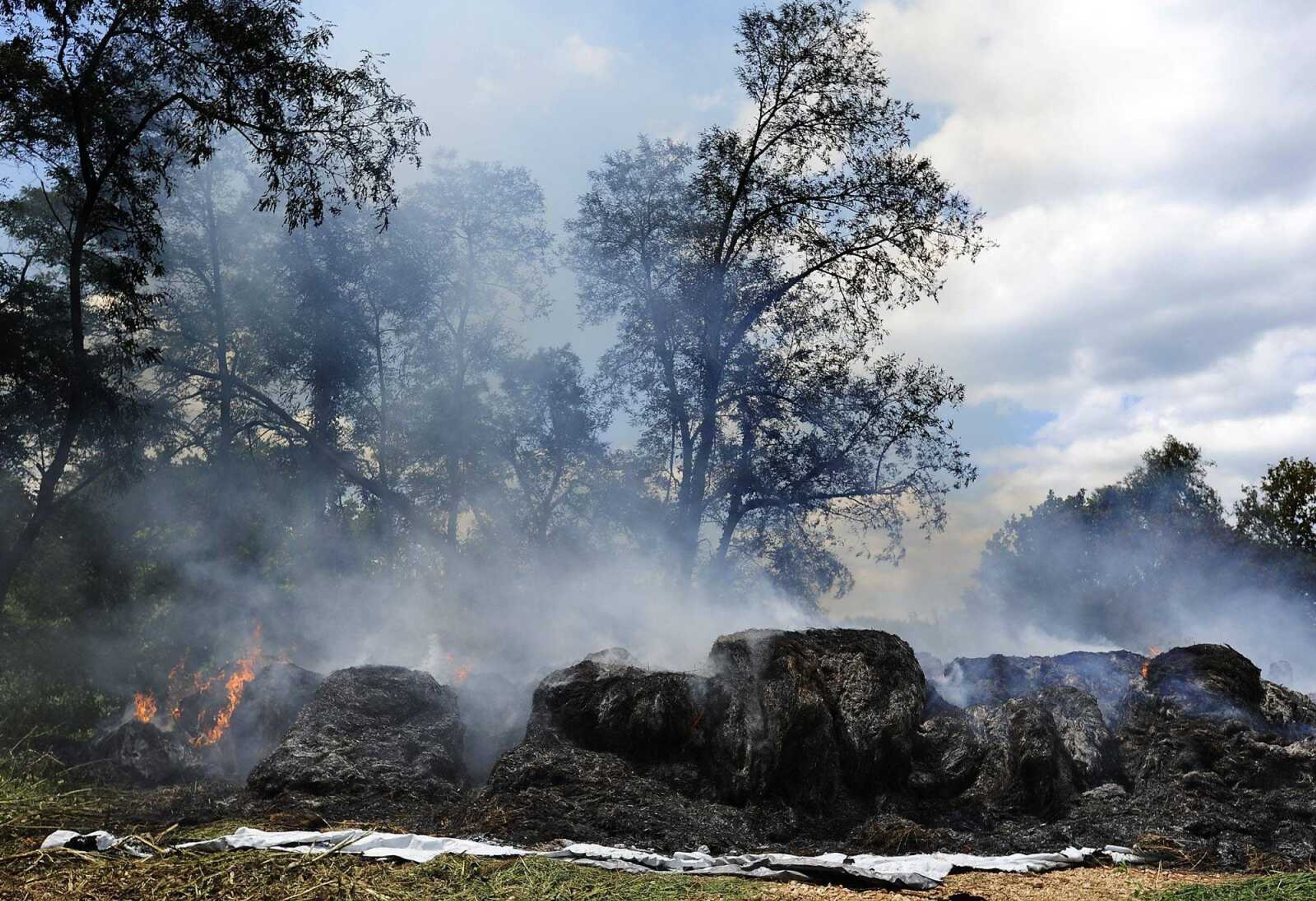 The remains of approximately 400 bales of hay smolder on the side of County Road 635 near it's intersection with County Road 637 Thursday, Aug. 15, in Cape Girardeau County. The cause of the fire, which was reported around 5:30 a.m. is under investigation. (Adam Vogler)