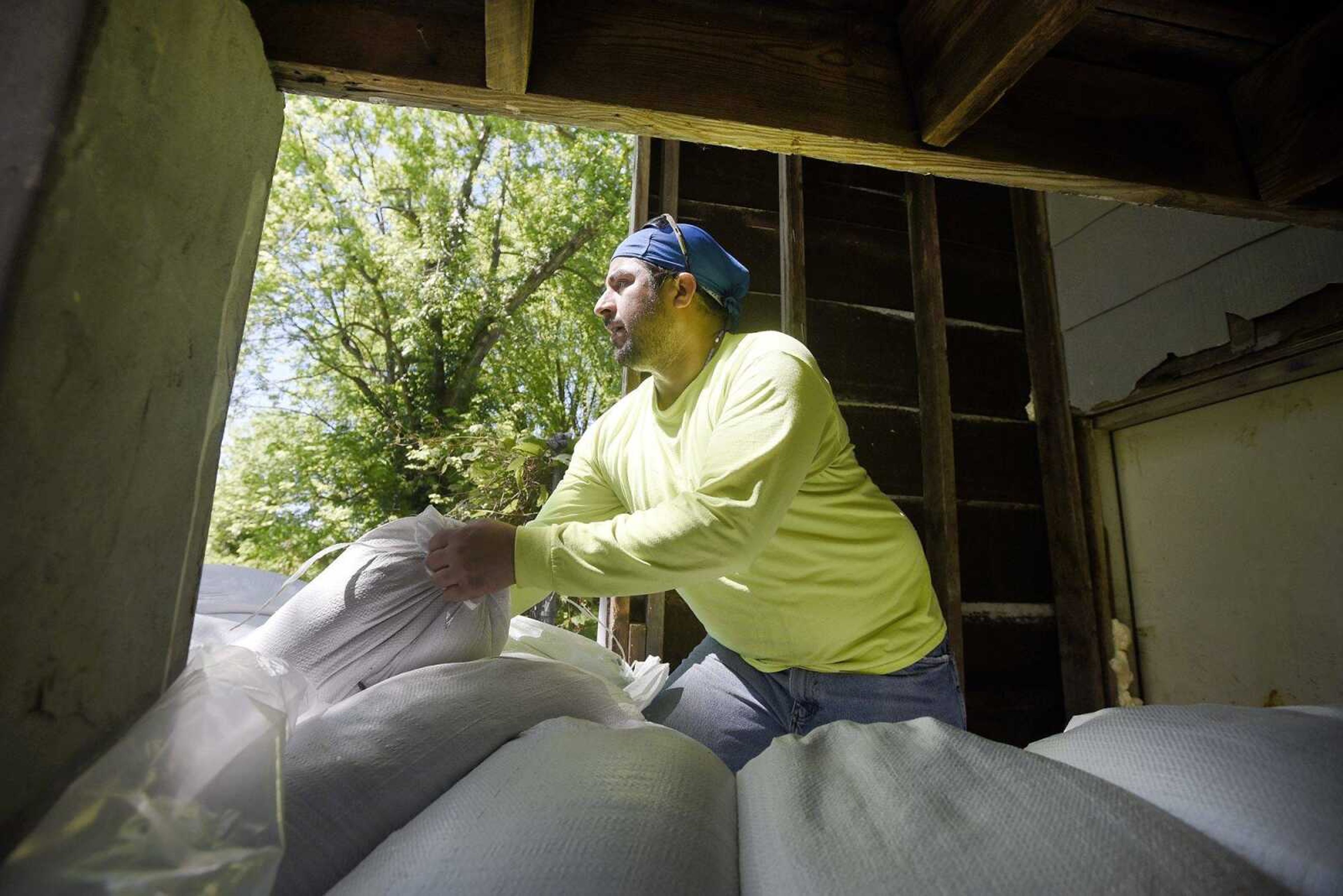 David Gomez places sandbags around the stairwell to the basement of his house Tuesday in the Red Star neighborhood of Cape Girardeau.