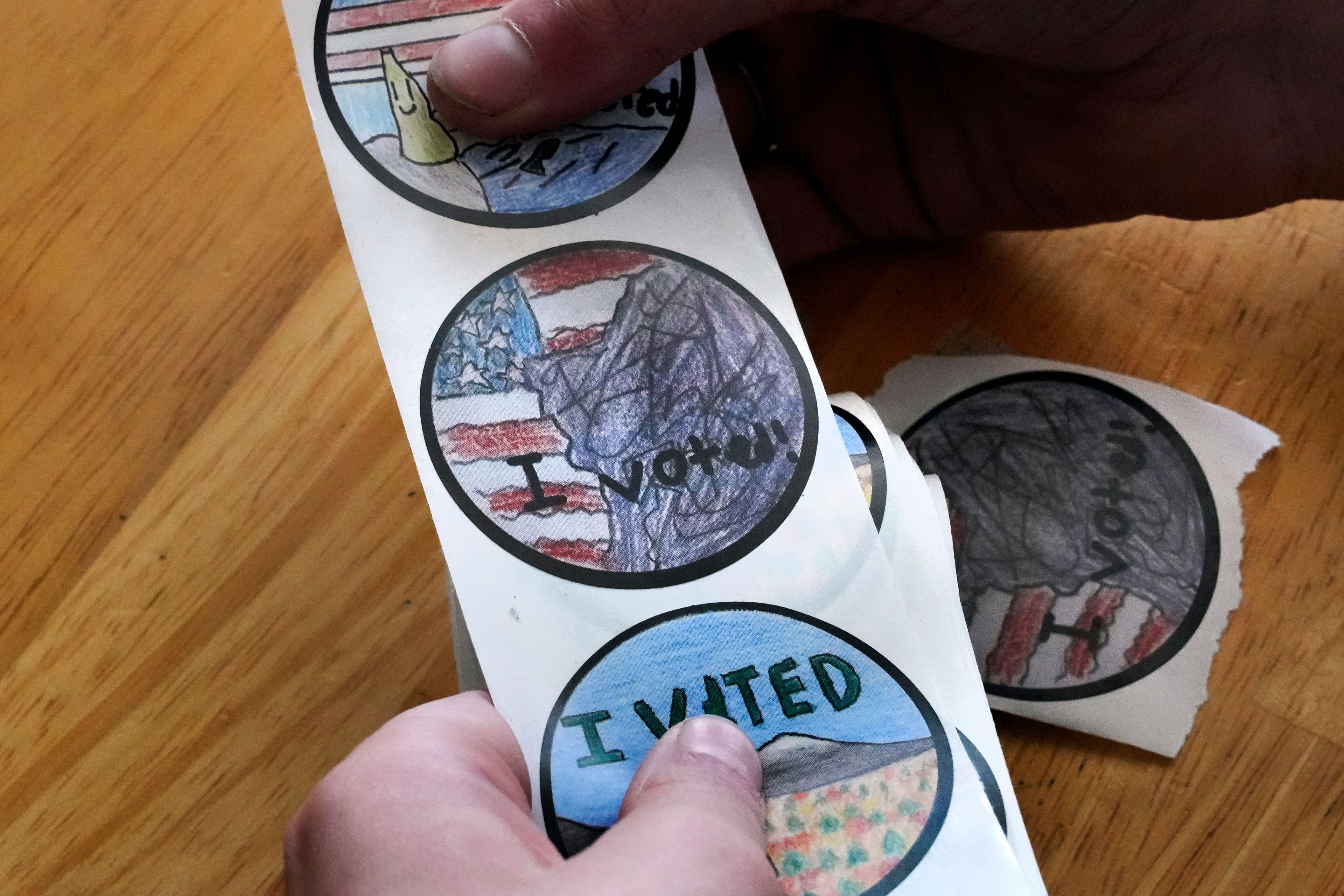 Ten-year-old Grace, of Milton, N.H. shows her contest winning "I Voted" sticker in her homeschool classroom, Thursday, Oct. 31, 2024, in Milton. Grace's design, inspired by a framed image of New Hampshire's famed Old Man of the Mountain at her home, features the landmark with an American flag in the background. (AP Photo/Charles Krupa)