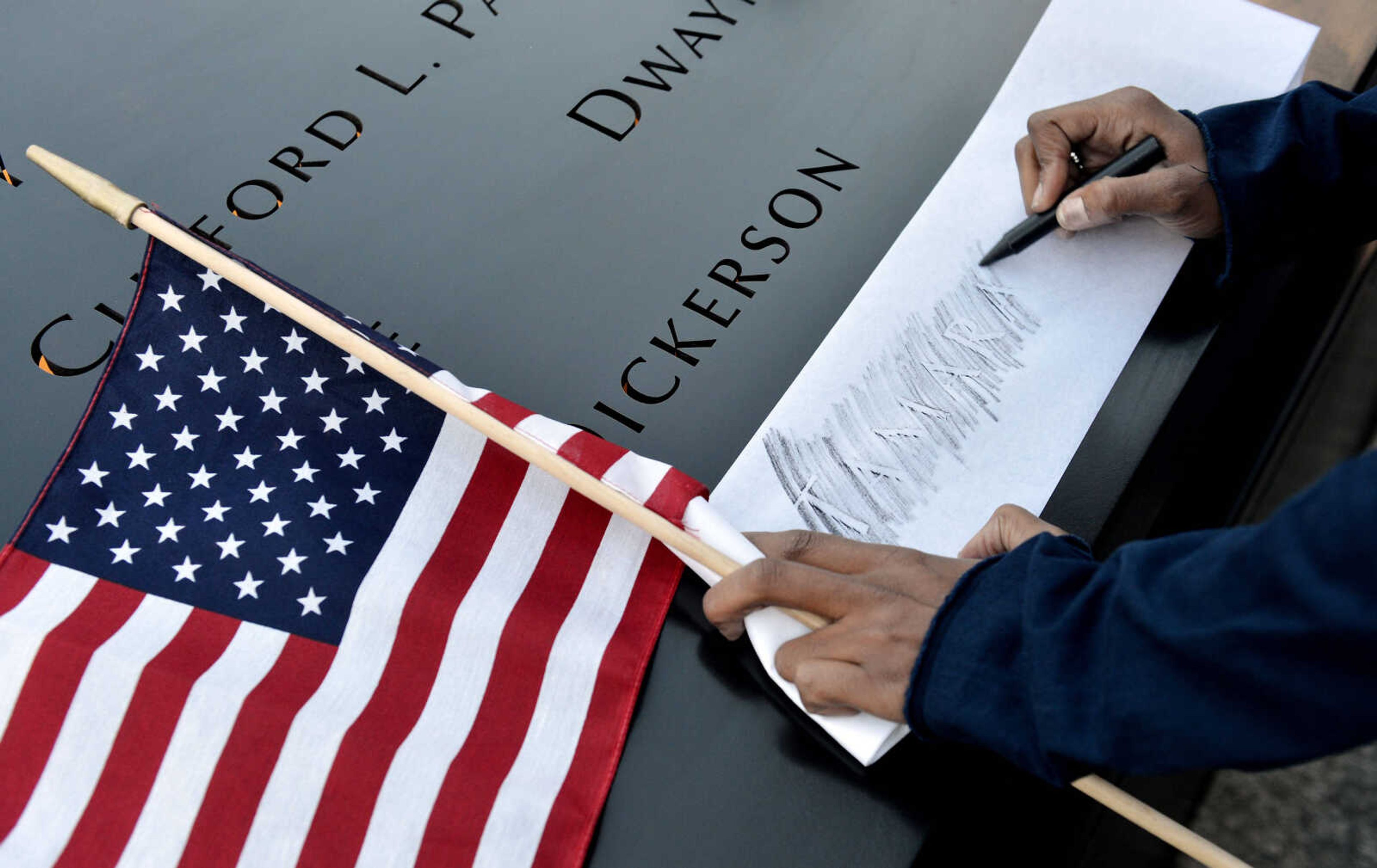 Alicia Watkins of Washington, D.C., makes a rubbing of a friend's name at the South Pool of the World Trade Center Memorial during the 11th anniversary observance of the 9/11 terrorist attacks in New York, Tuesday, Sept. 11, 2012. (AP Photo/Justin Lane, Pool)