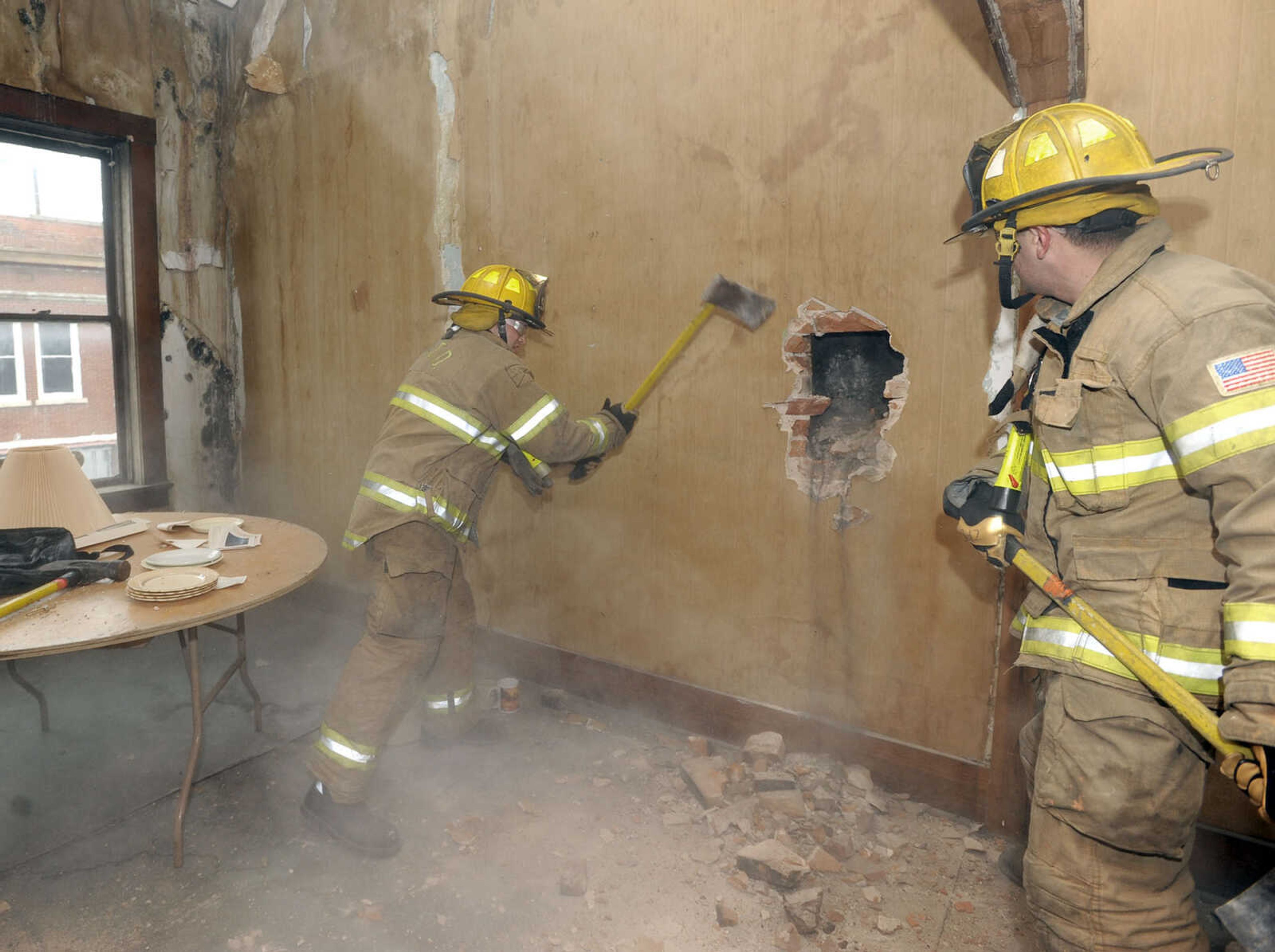 Firefighters Jamie Hann, left, and Drew Goodale practice wall breaching.