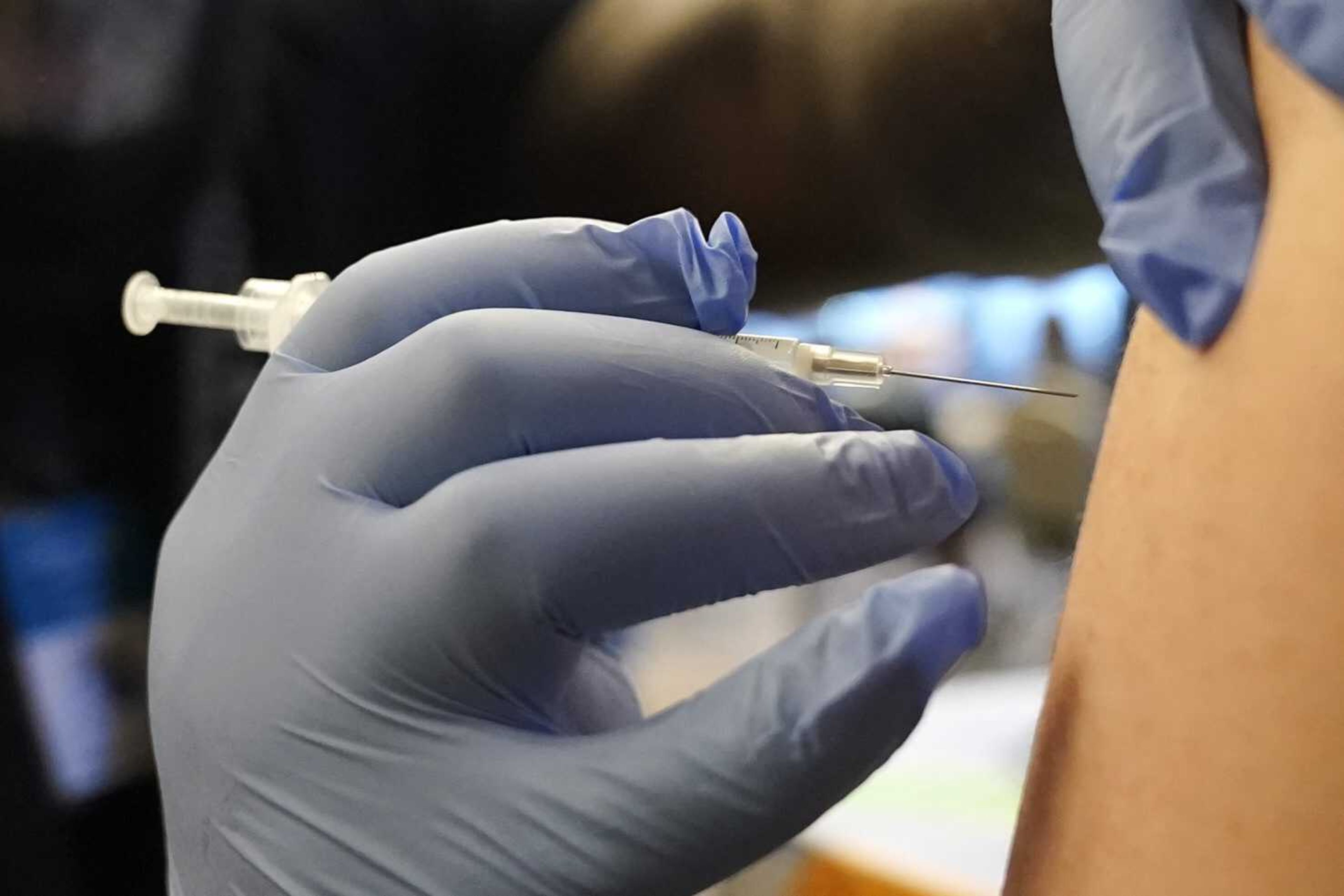 DeMarcus Hicks, a recent graduate of nursing school who is working as a contractor with the Federal Emergency Management Agency, gives a person a Pfizer COVID-19 vaccine booster shot Dec. 20 in Federal Way, Washington. A federal appeals court on Thursday has upheld President Joe Biden's requirement all federal employees be vaccinated against COVID-19.