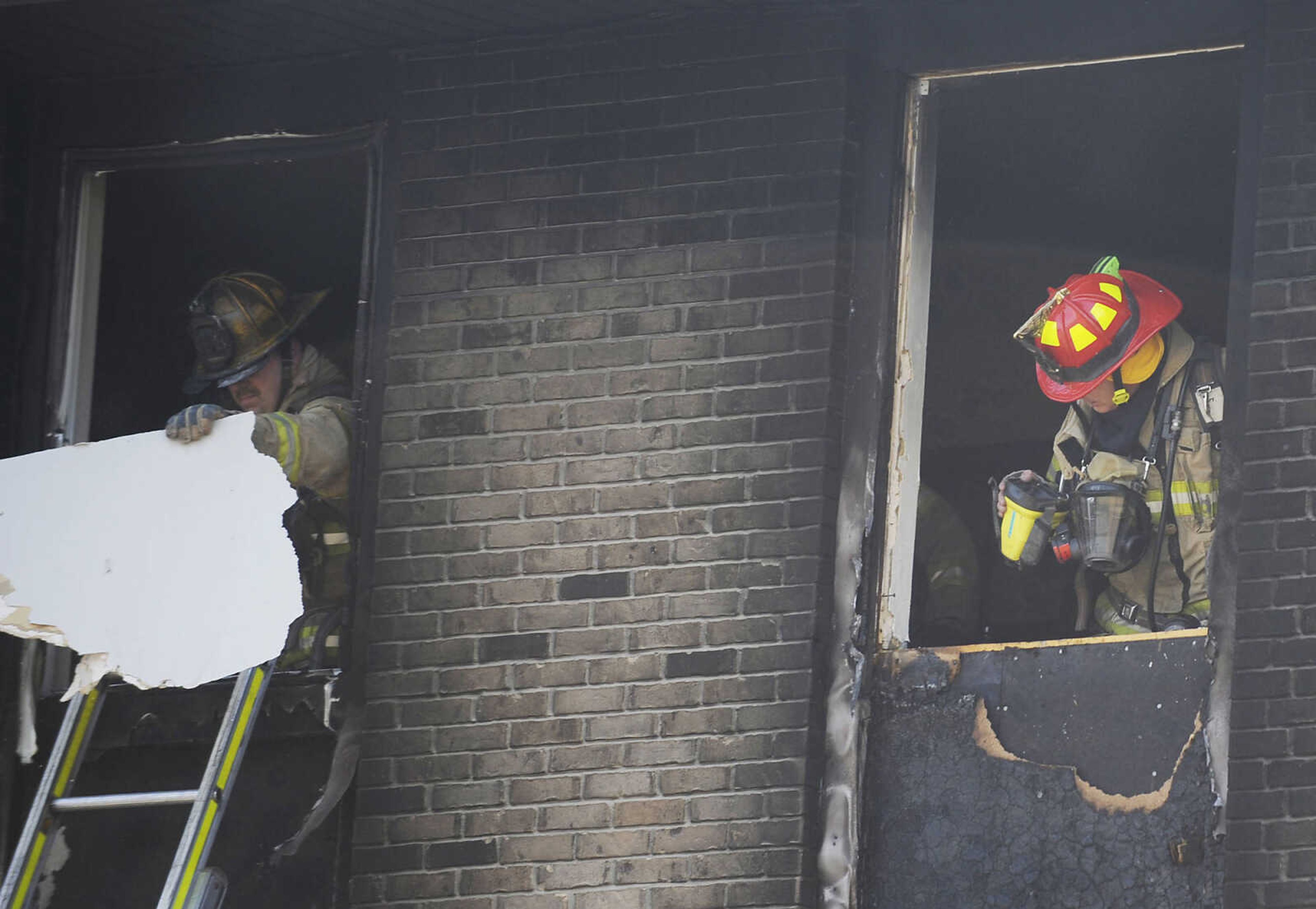 Members of the Cape Girardeau Fire Department remove debris and check for hot spots after a fire Thursday, July 12, in an apartment building at 121 E. Rodney. The fire began in a ground floor unit in building H of the apartment complex and spread to the upper story according to Capt. Ray Warner. The occupant of the upper level unit had to be rescued by fire fighters. The resident of the apartment where the fire began escaped on her own but later asked to be treated for smoke inhalation and was transported to a hospital. (Adam Vogler)