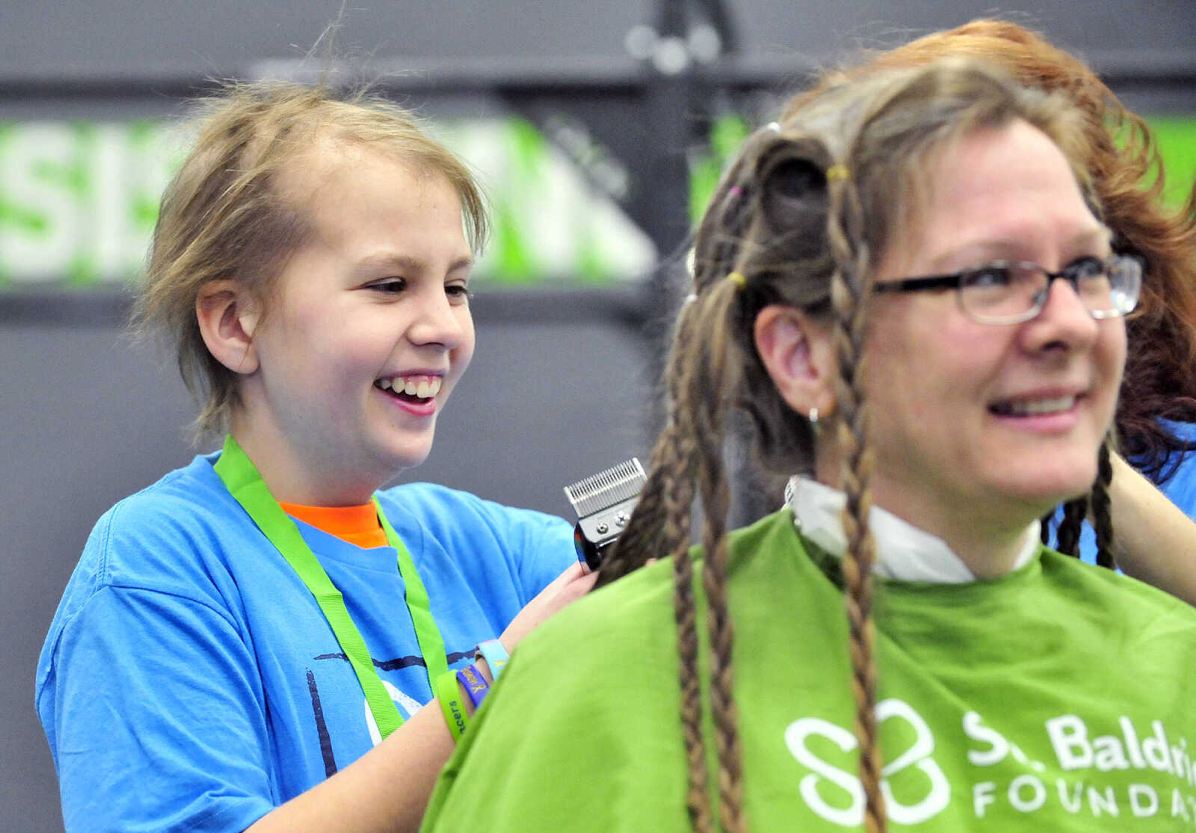 Sarah Singleton, 13, shaves part of her mother's, Jennifer, hair off with assistance from April Whiteside on Saturday, March 4, 2017, during the St. Baldrick's Foundation fundraiser at Old Orchard CrossFit in Jackson.