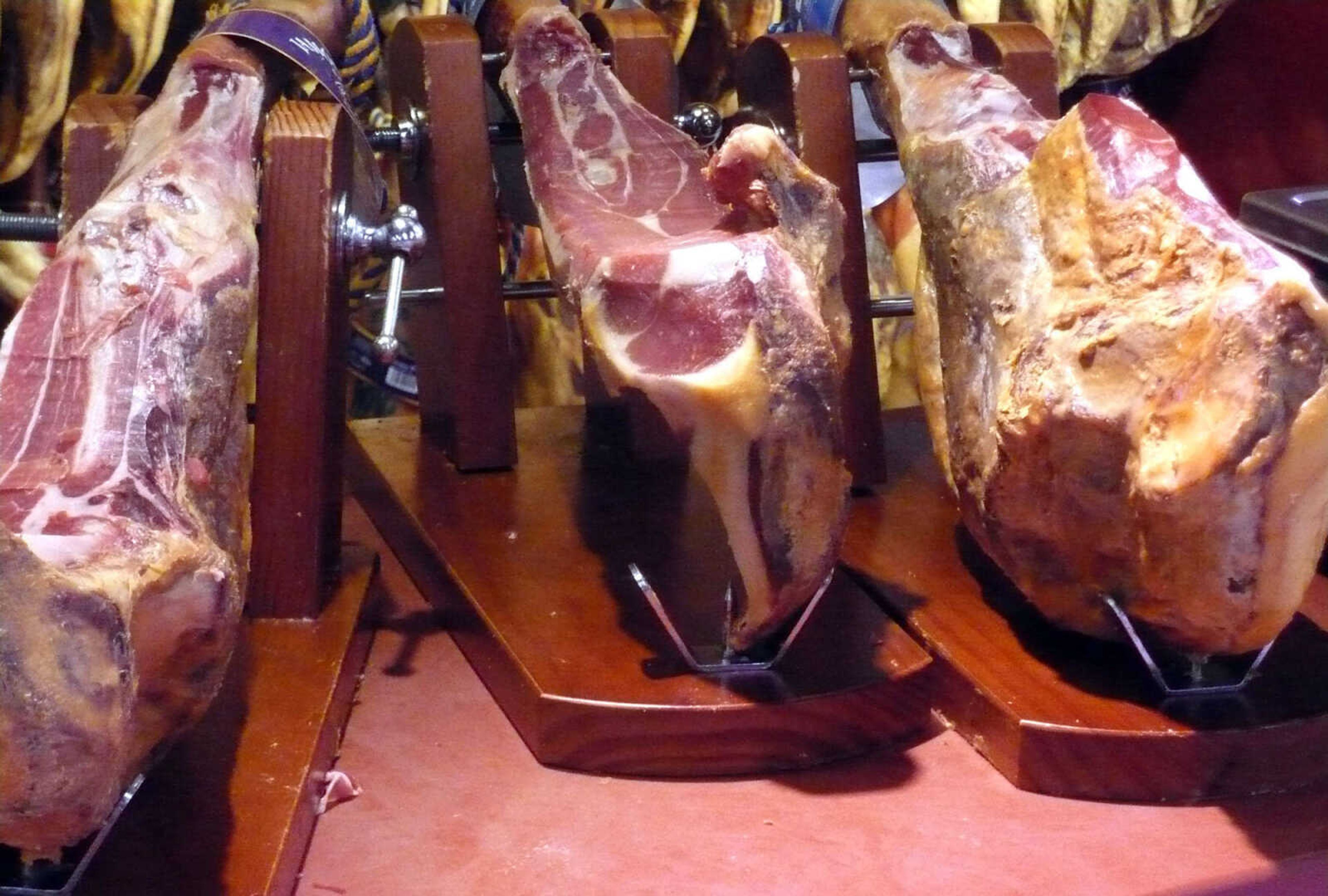 A variety of Spanish hams await carving in the deli department of a Spanish grocery store.