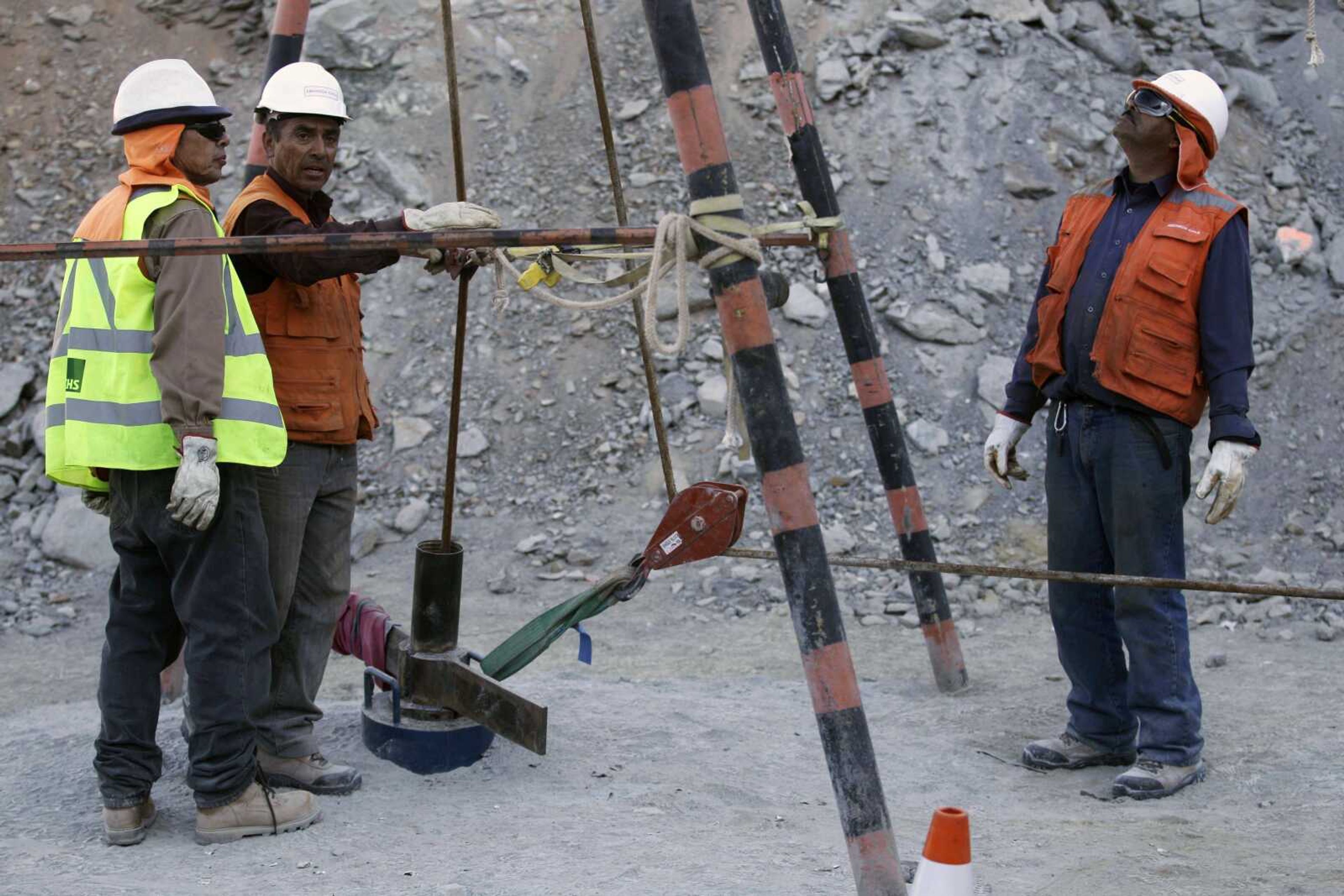 Men work on a pipe used to stay in touch with 33 trapped miners at the San Jose collapsed mine in Copiapo, Chile, on Wednesday. The miners, who have been trapped since the shaft they were working in collapsed Aug. 5, were confirmed to be alive Sunday when they were reached by rescue teams via a small hole through which they could pass messages, supplies, air, and see the miners with a camera. (Roberto Candia ~ Associated Press)