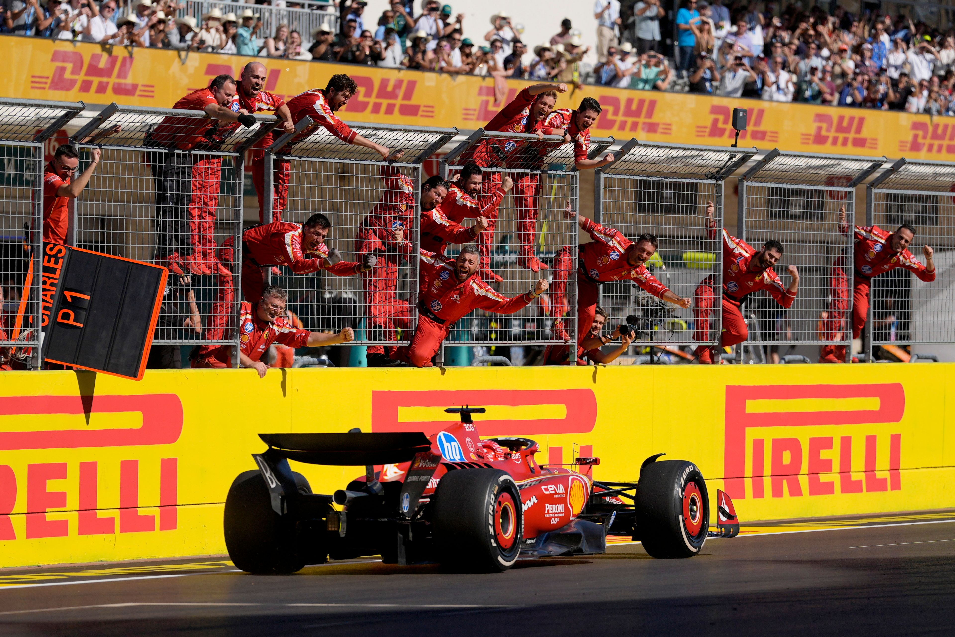 Team members stand along the fence celebrating as Ferrari driver Charles Leclerc, of Monaco, wins the U.S. Grand Prix auto race at Circuit of the Americas, Sunday, Oct. 20, 2024, in Austin, Texas. (AP Photo/Eric Gay)