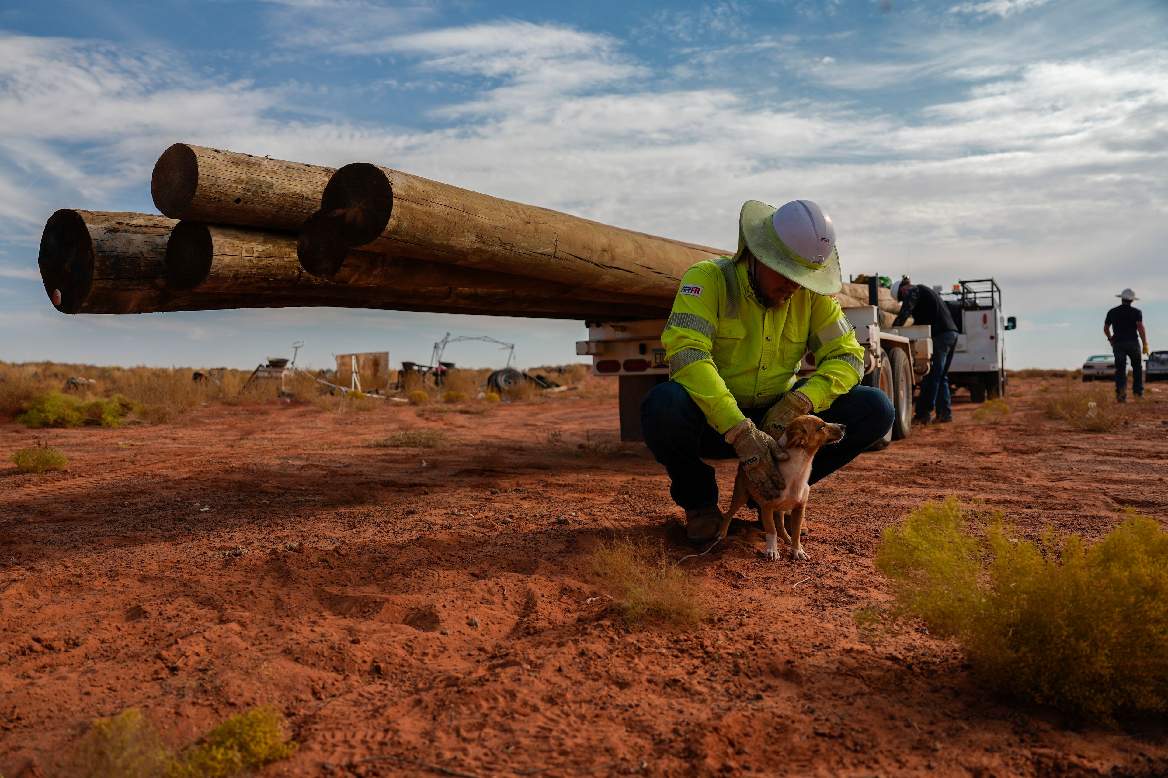 A volunteer pets a dog before starting power line construction for a home, Tuesday, Oct. 8, 2024, on the Navajo Nation in Halchita, Utah. (AP Photo/Joshua A. Bickel)