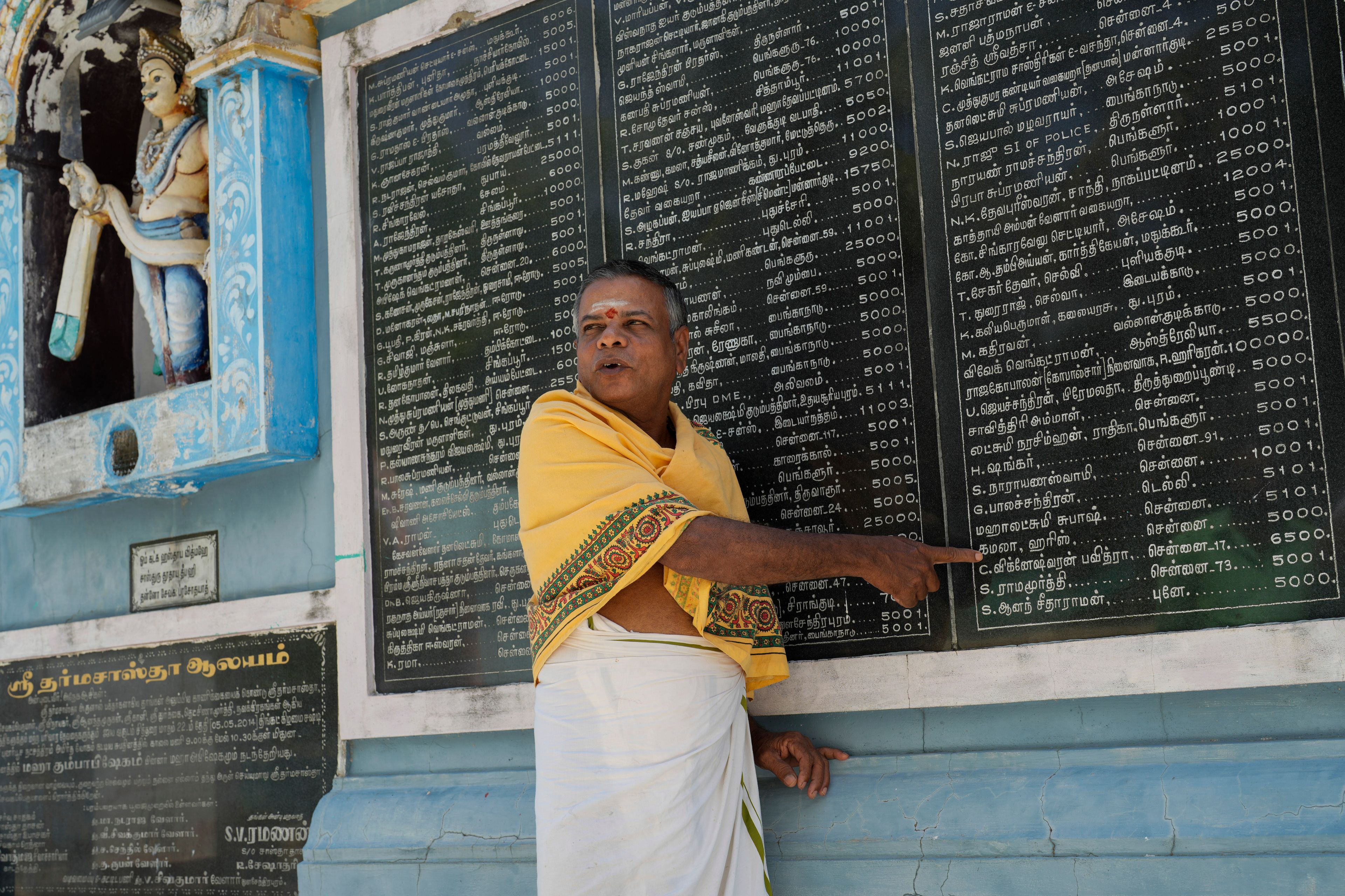 M. Natarajan, head priest of Sri Dharmasastha Hindu temple points out the name of Democratic presidential nominee Vice President Kamala Harris on a plaque, displaying names of donors written in Tamil language who donated for the renovation of temple, in Thulasendrapuram, the ancestral village of Harris, in Tamil Nadu state, India, Monday, Nov. 4, 2024. (AP Photo/Aijaz Rahi)