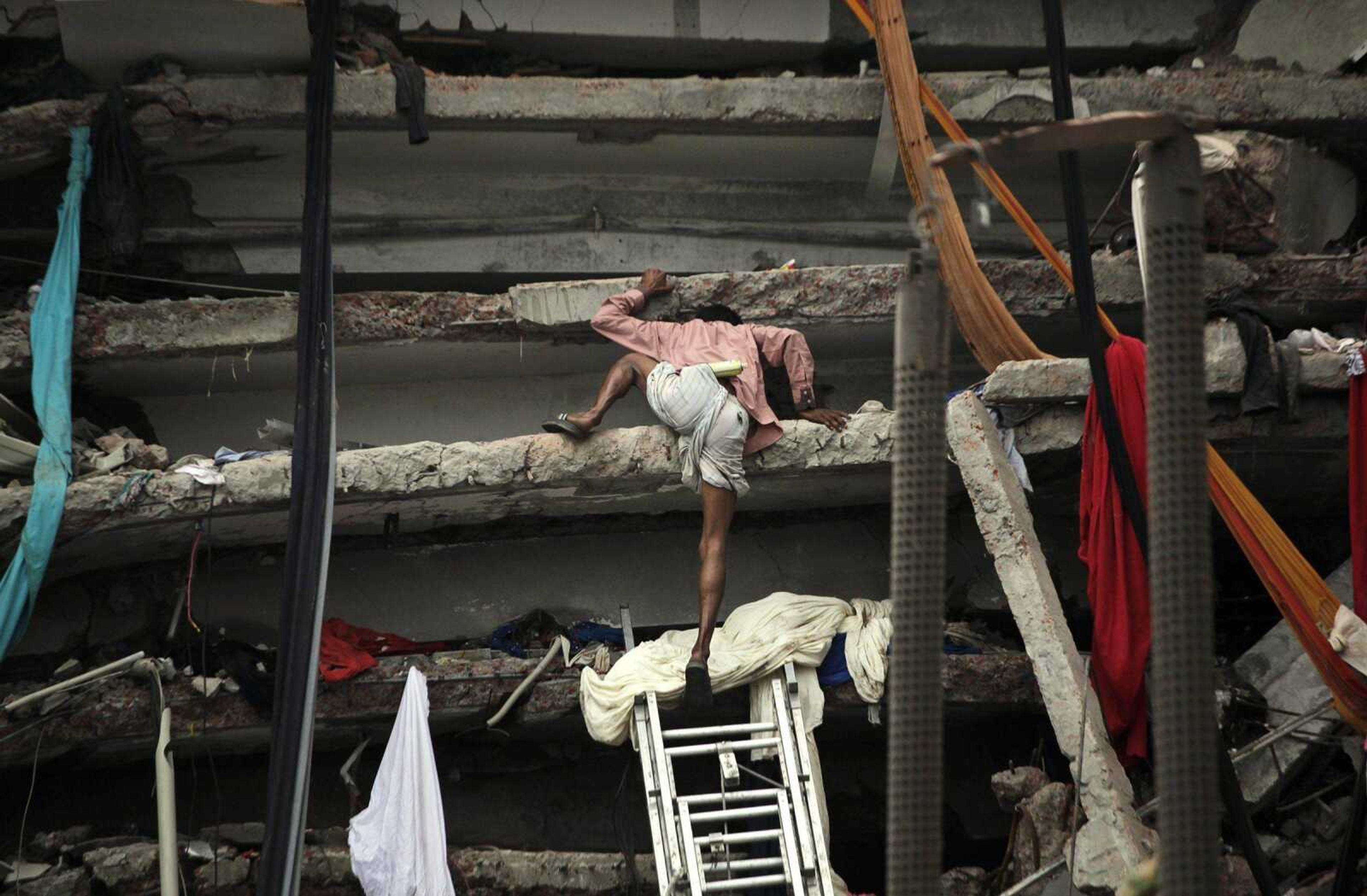 A Bangladeshi civilian rescue volunteer on Saturday climbs a section of a building that collapsed Wednesday in Savar, near Dhaka, Bangladesh. (Kevin Frayer ~ Associated Press)