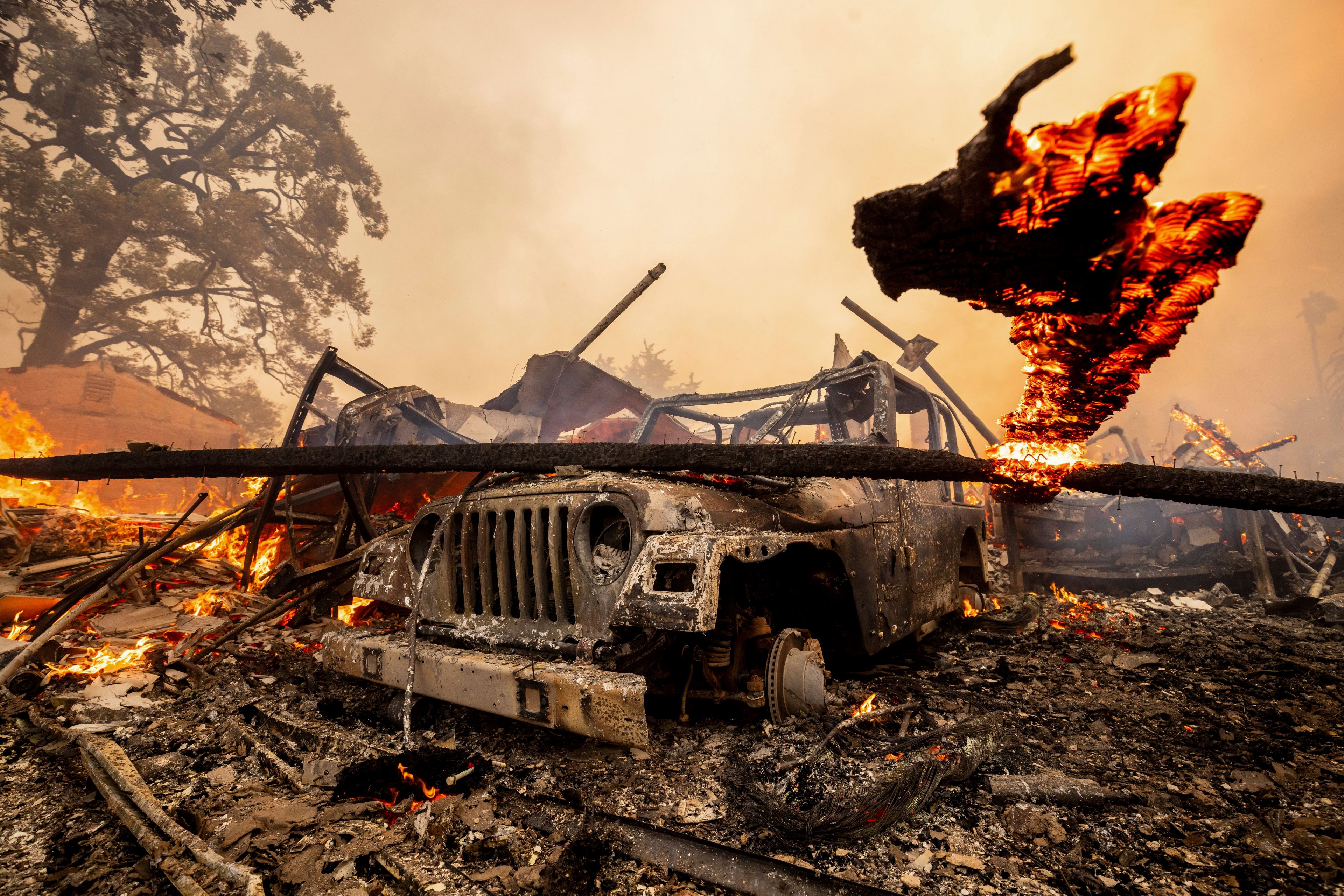 A burned vehicle sits among a destroyed home in the Mountain Fire, Nov. 6, 2024, near Camarillo, Calif. (AP Photo/Ethan Swope)