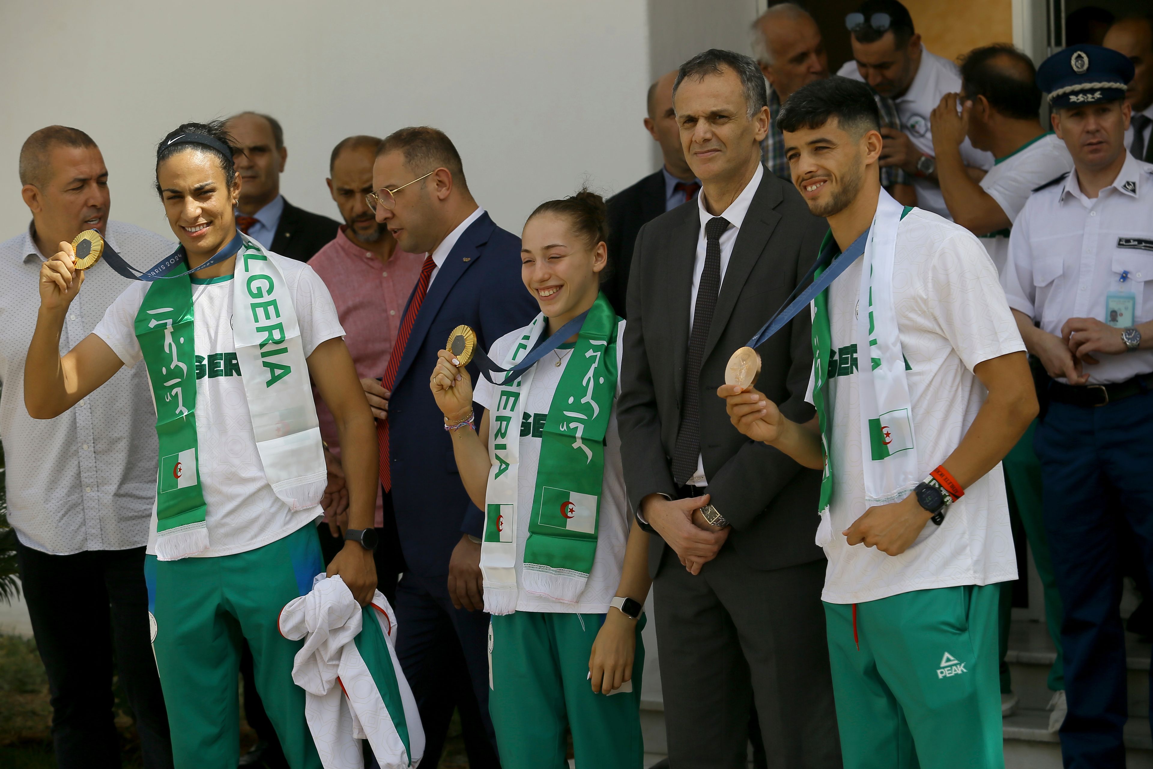 Gold medalist in the the women's 66 kg boxing Algeria's Imane Khelif, left, French-Algerian gymnast gold medalist in the uneven bars Kaylia Nemour, center, and bronze medalist in the men's 800m Djamel Sedjati show their medals after the 2024 Summer Olympics, Monday, Aug. 12, 2024, at Algiers airport, Algeria. (AP Photo/Anis Belghoul)