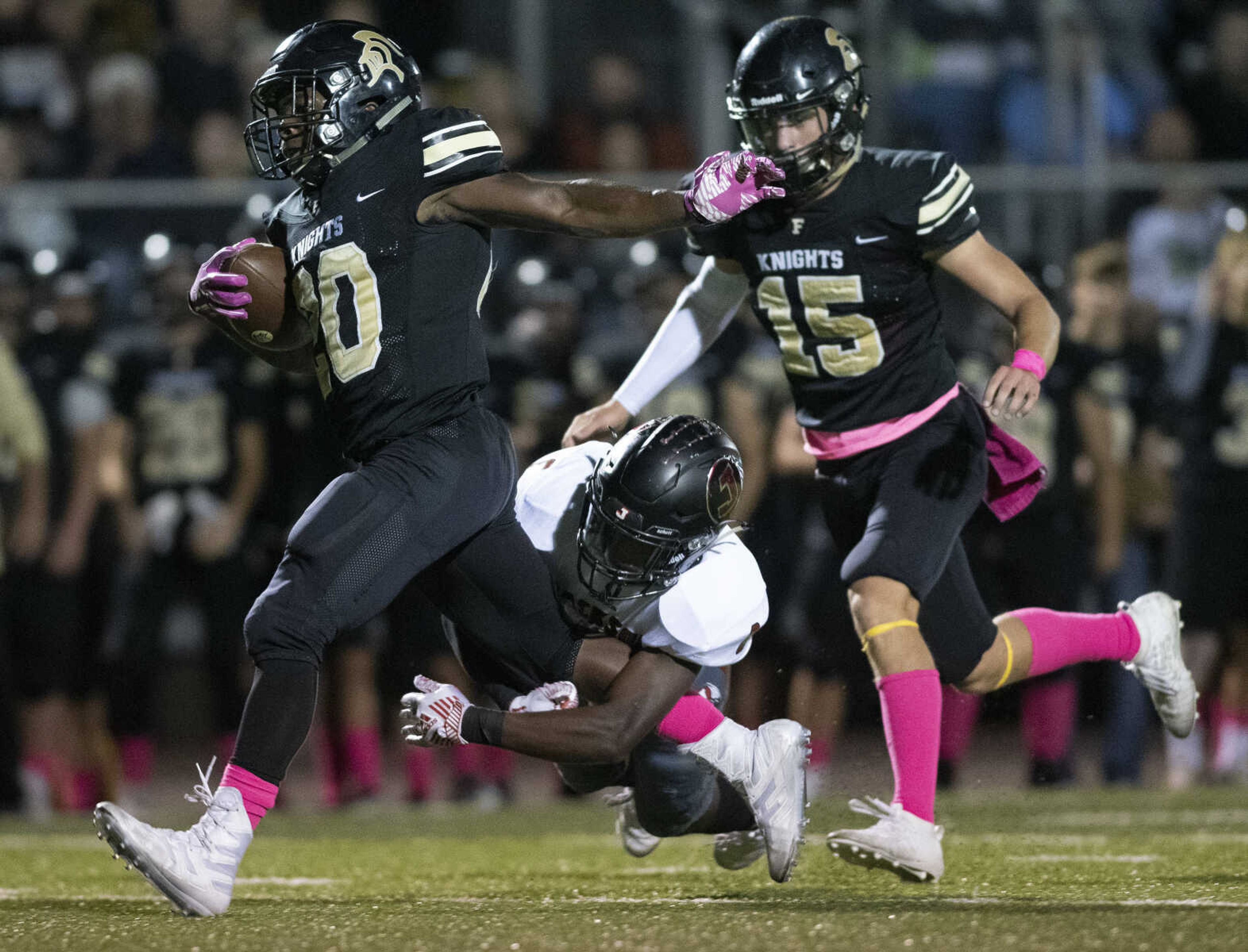 Jackson's Markiese Jones (8), in white, attempts to take down Farmington's Royce Harris (20) near Eli Lamb (15) during the Jackson Indians' matchup against Farmington on Friday, Oct. 4, 2019, in Farmington, Missouri.