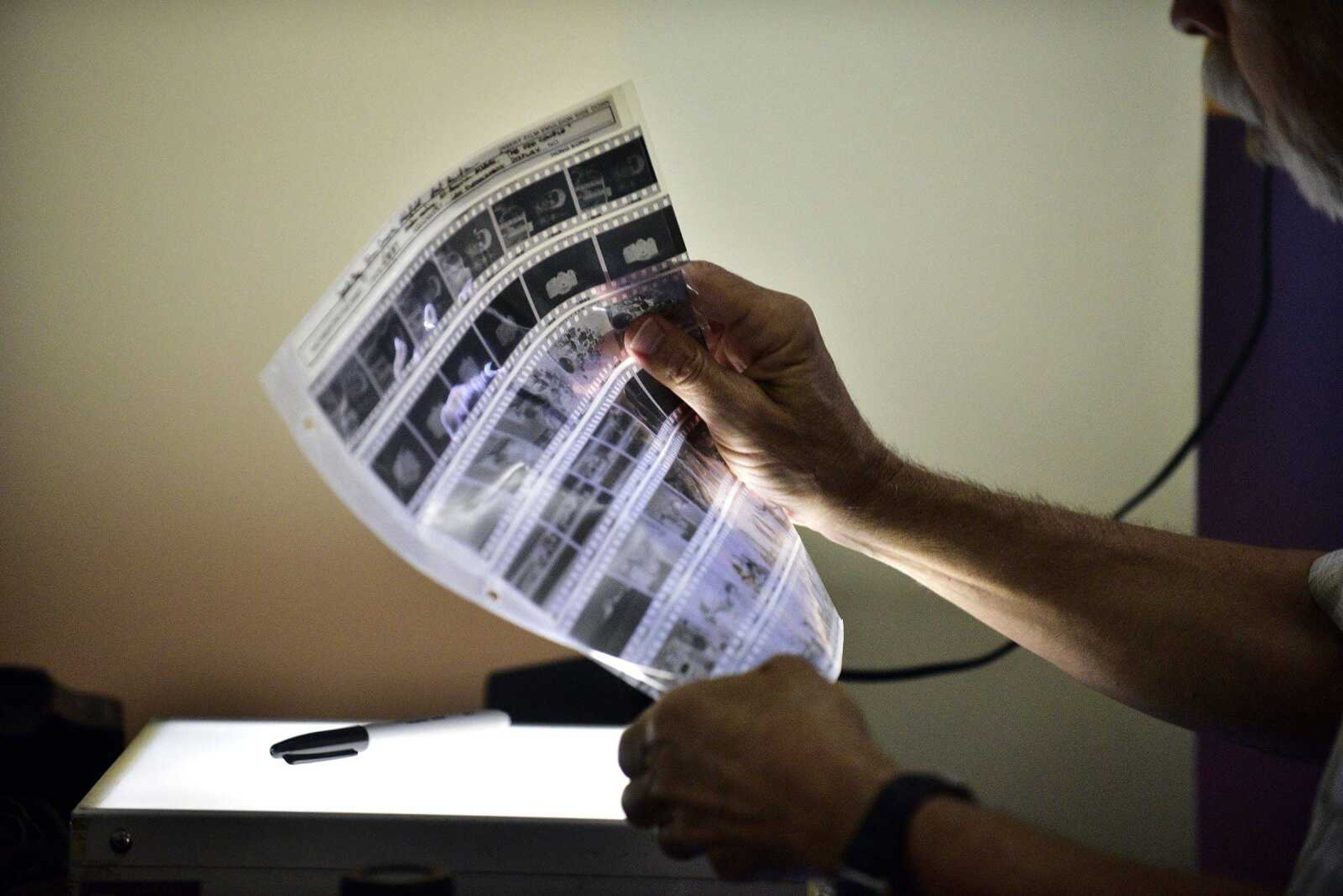 Southeast Missourian photojournalist, Fred Lynch, looks through a sleeve of old black and white negatives in the photo office on Friday, June 9, 2017.