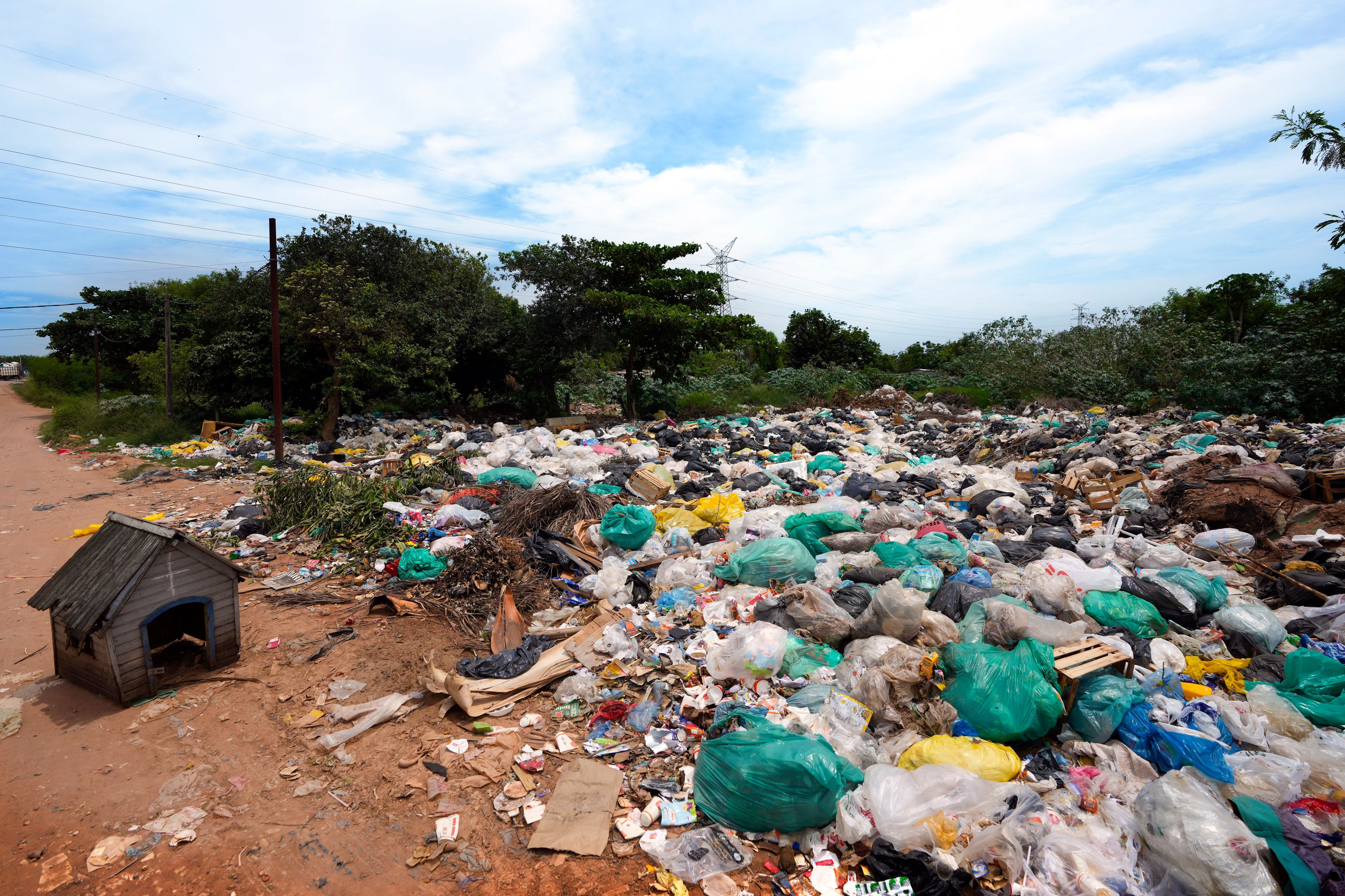 FILE- An abandoned dog house sits alongside a landfill covered with discarded plastic materials in Asuncion, Paraguay, Tuesday, Nov. 26, 2024. (AP Photo/Jorge Saenz, File)