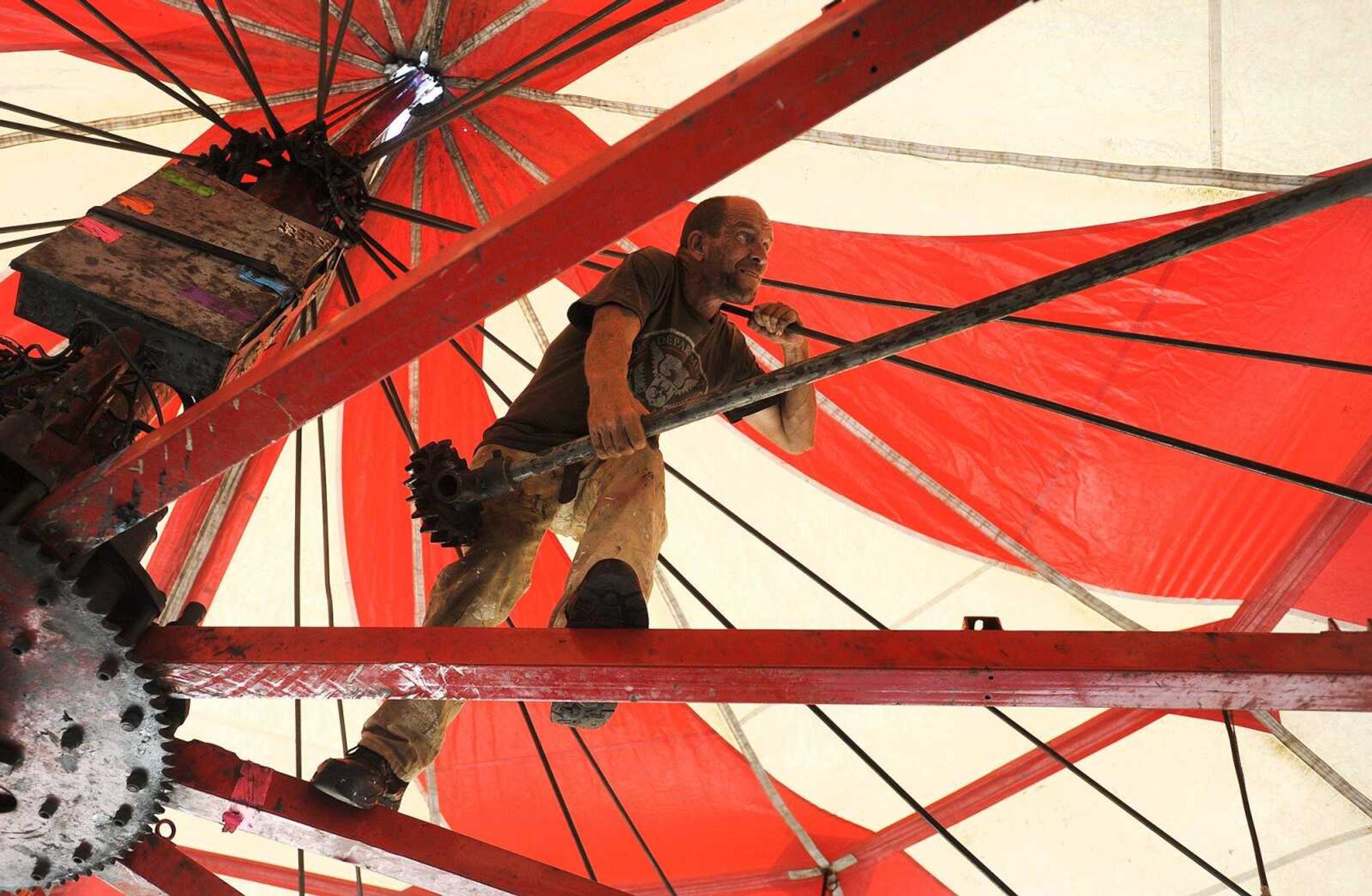 John Doolin of the Lowery Carnival Co. works on assembling the carousel in the midway Tuesday for the SEMO District Fair at Arena Park. The annual fair begins Saturday.