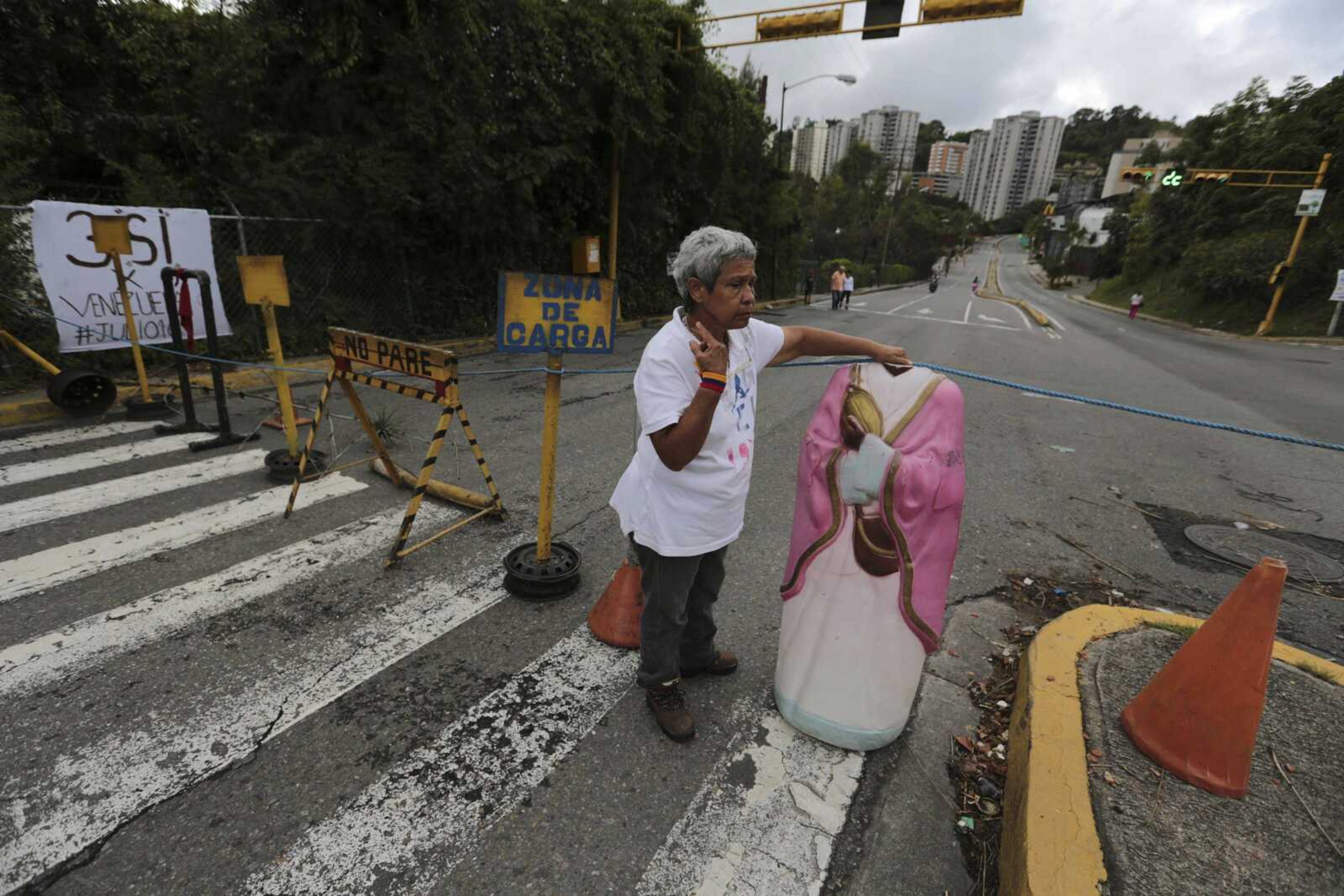 A woman builds a road barricade Thursday to protest against Venezuela's President Nicolas Maduro in Caracas, Venezuela.