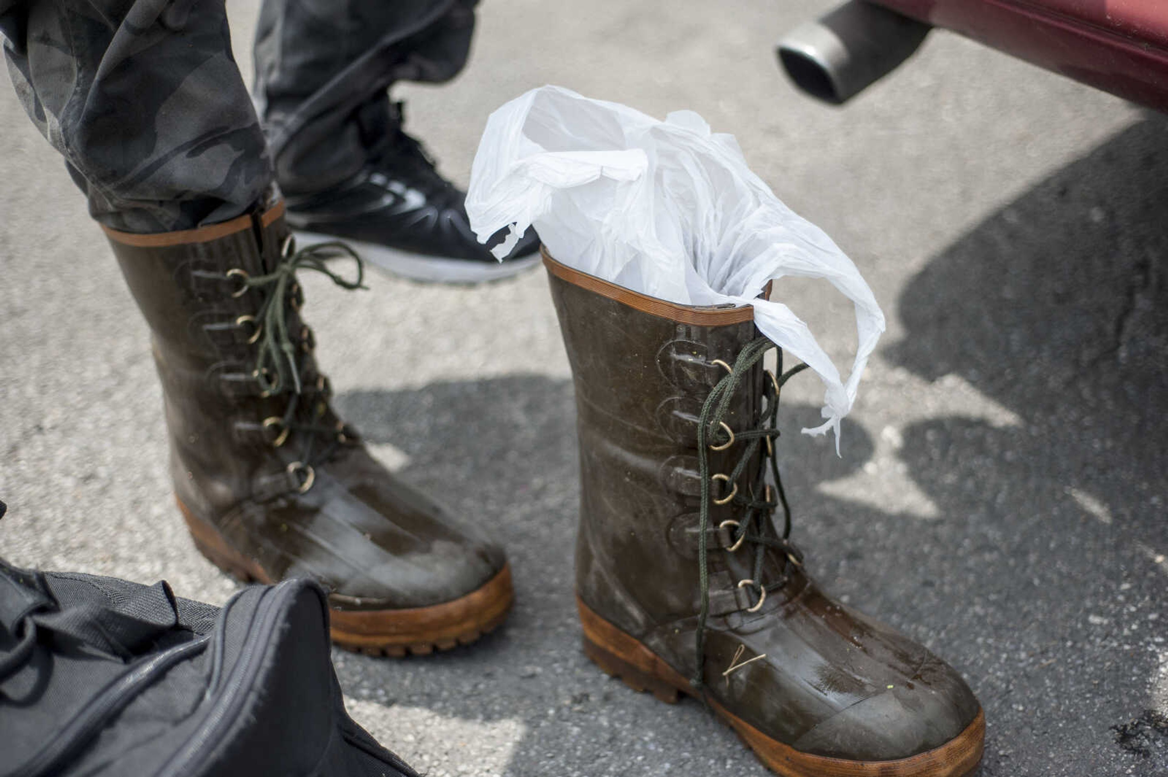 Brian Winans changes out of his boots, which he lines with plastic bags for extra insulation, Saturday, July 17, 2019, in East Cape Girardeau, Illinois.