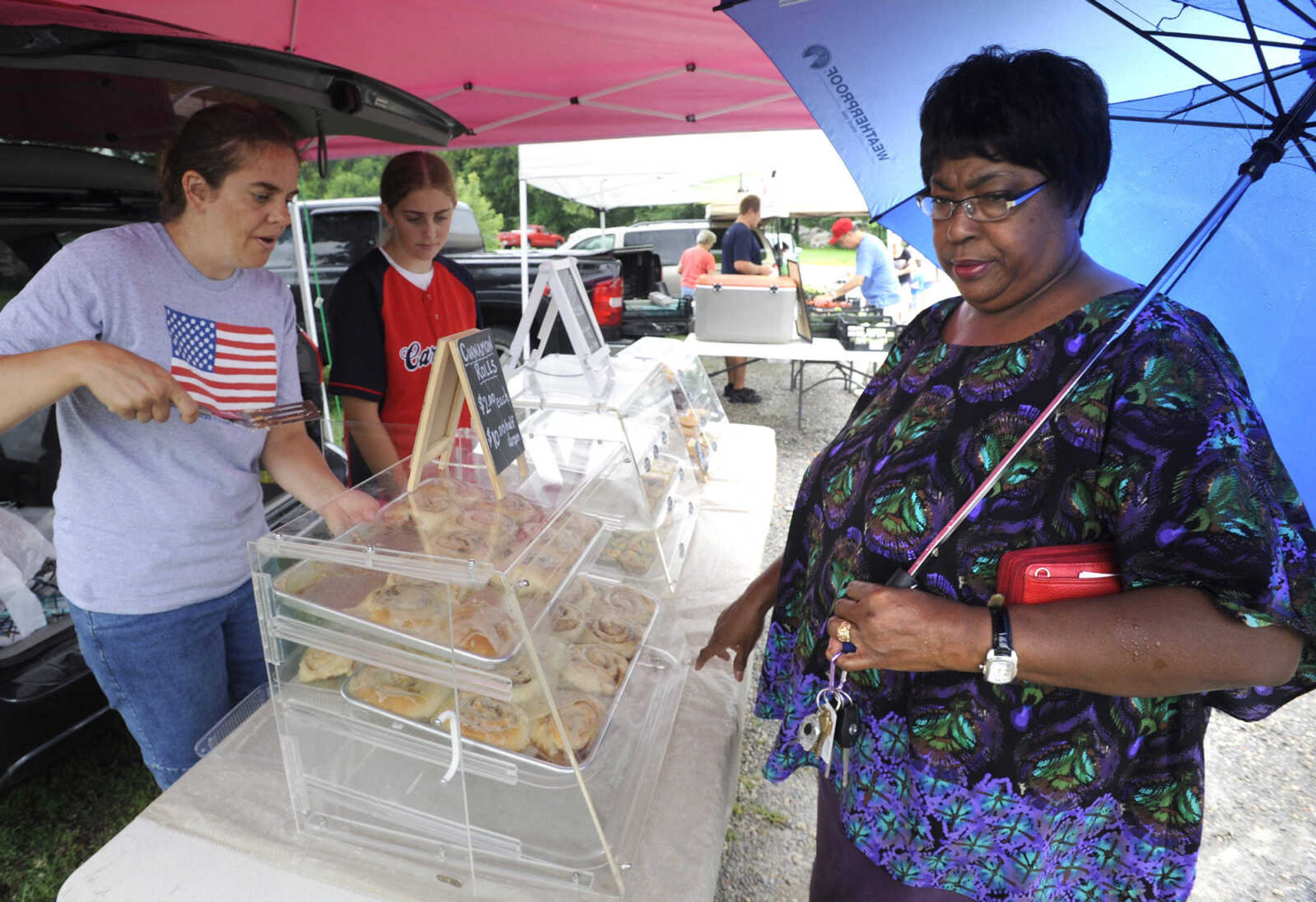 Amy Stafford of Jackson checks out the cinnamon rolls offered by Michelle Chesser, left, and her daughter, Katie, Tuesday, July 7, 2015 at the Jackson Farmer's Market in Jackson.