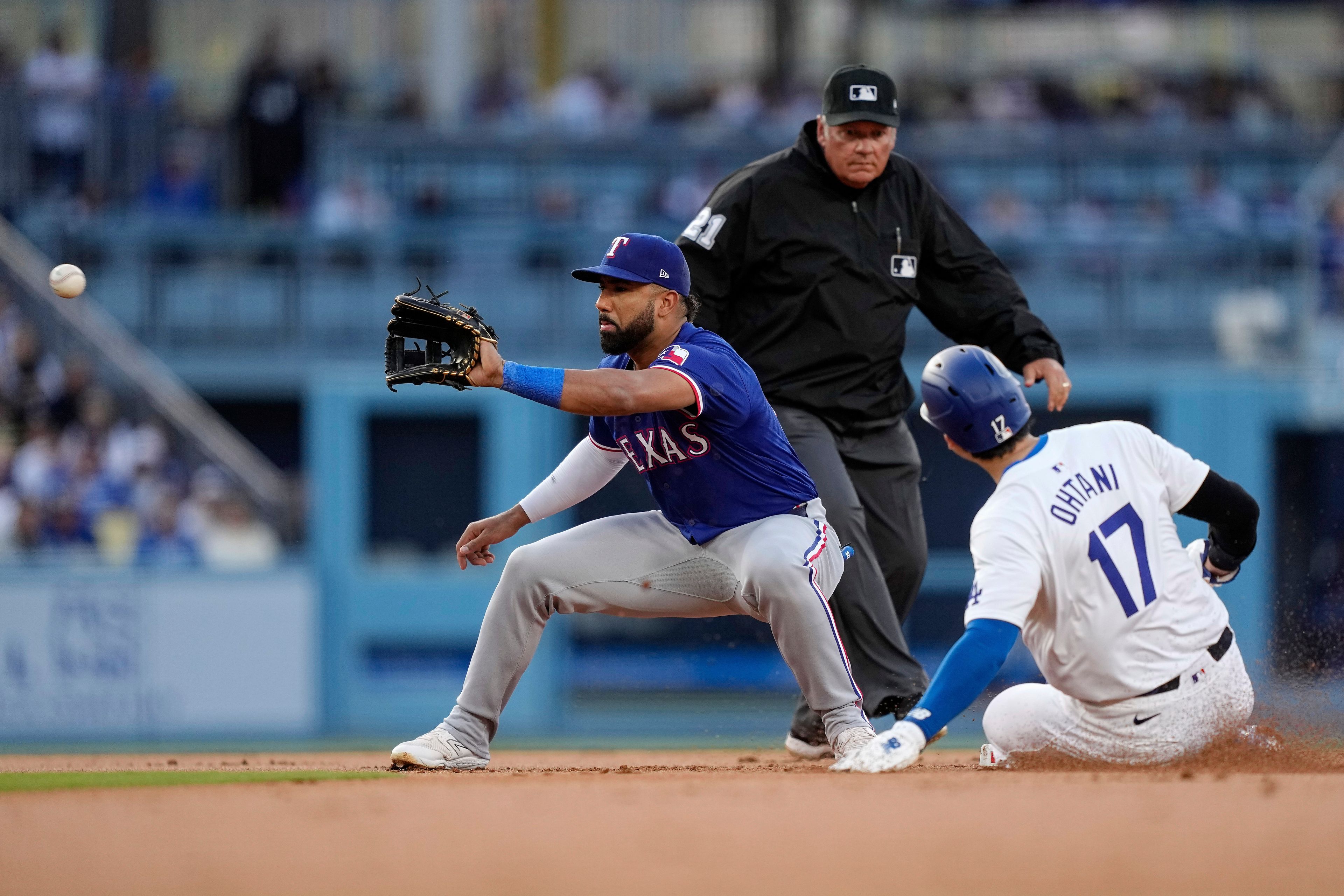 Los Angeles Dodgers' Shohei Ohtani, right, steals second as Texas Rangers shortstop Ezequiel Duran, left, takes a late throw while second base umpire Hunter Wendelstedt watches during the first inning of a baseball game Tuesday, June 11, 2024, in Los Angeles. (AP Photo/Mark J. Terrill)