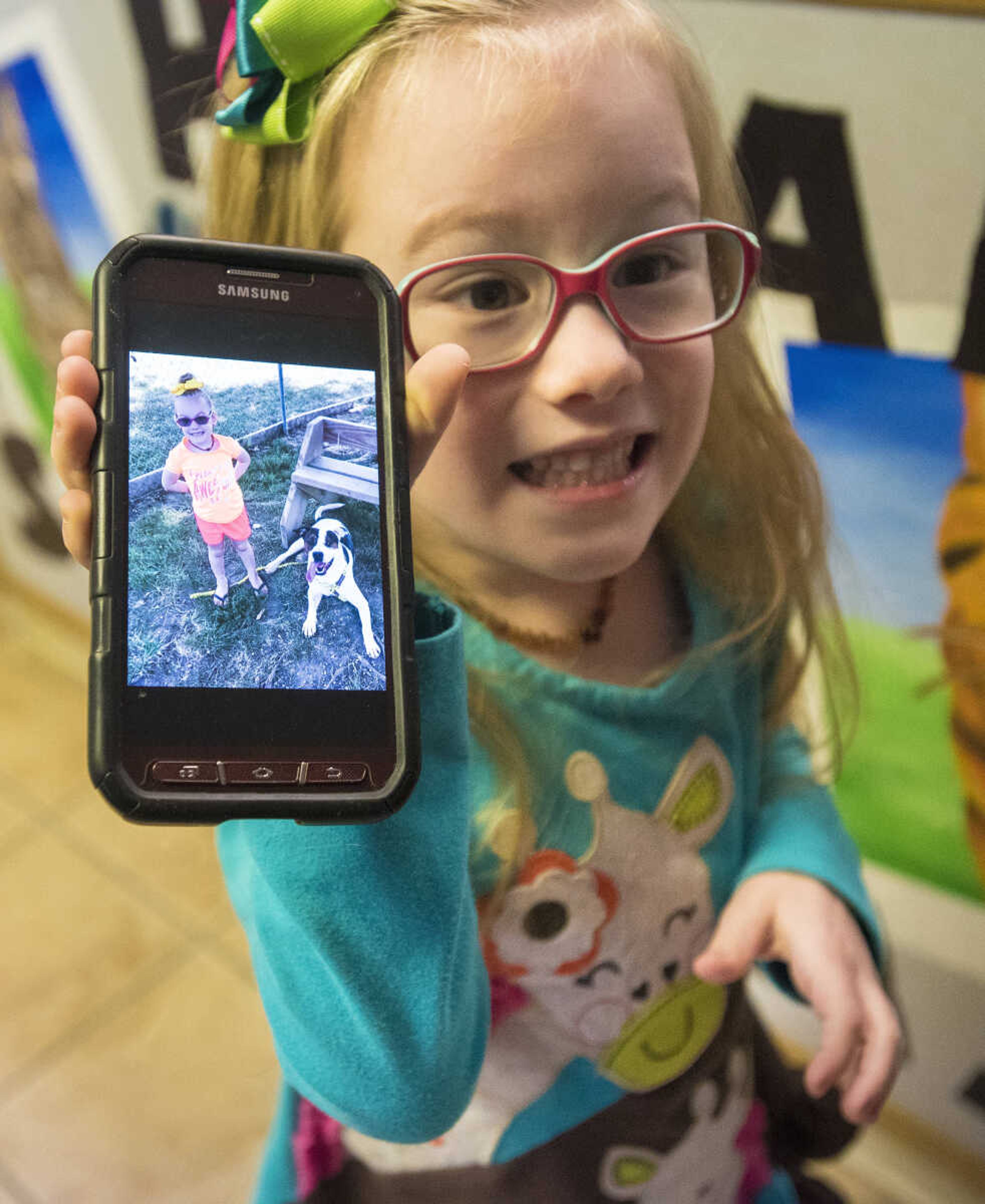 Mercy Stephens, 5, shows a photo of the adopted dog, Max, at the 40th anniversary of the Humane Society of Southeast Missouri Saturday, Dec. 16 , 2017 in Cape Girardeau. Max is part of the Puppies for Parole program that allow dogs to become trainers for those in need of assistance. Mercy will use Max for her vision impairments.