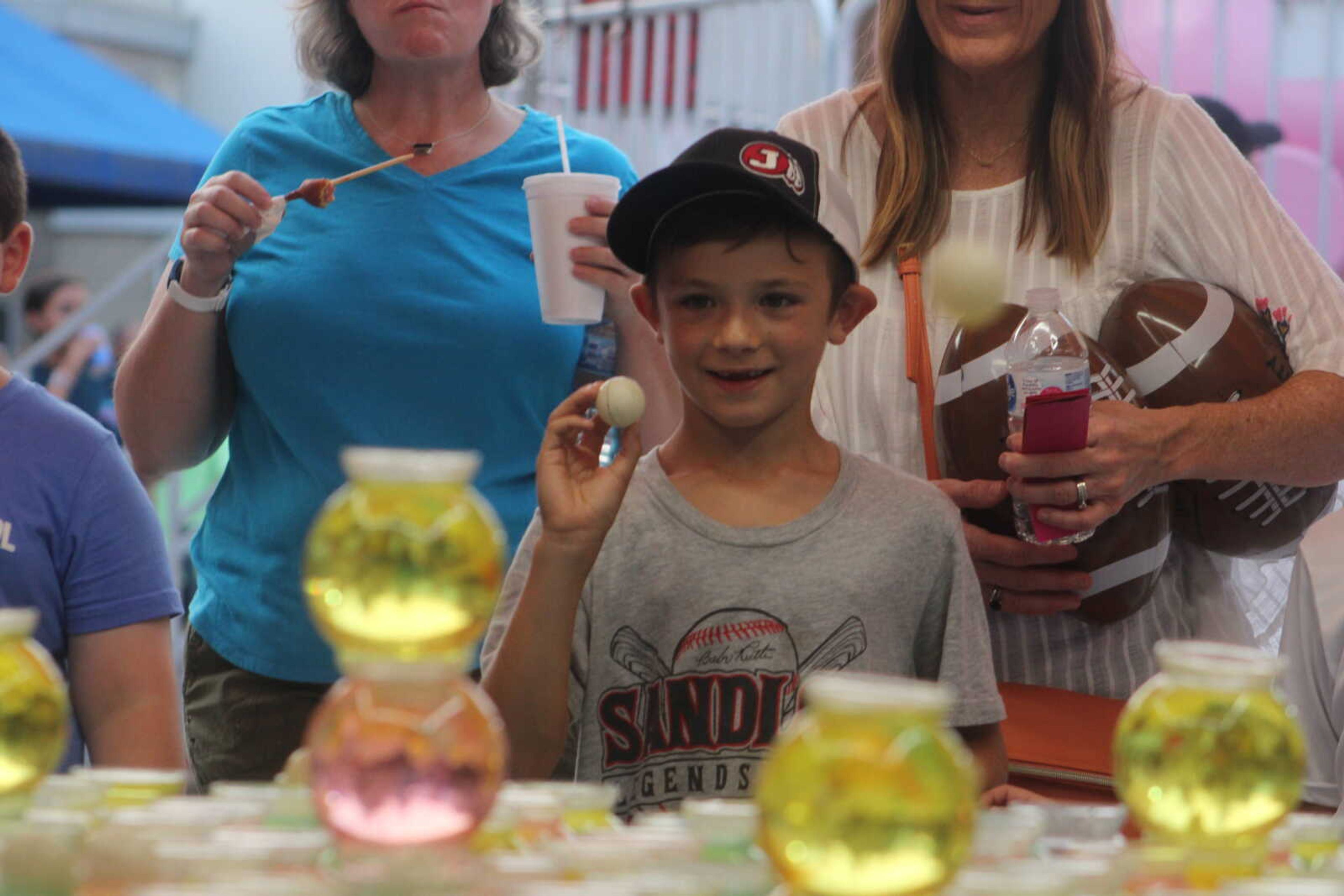 Sawyer Clifton prepares to toss a ping pong ball into a fishbowl to win a goldfish during Jackson Homecomers Wednesday, July 28, 2021, in Uptown Jackson.