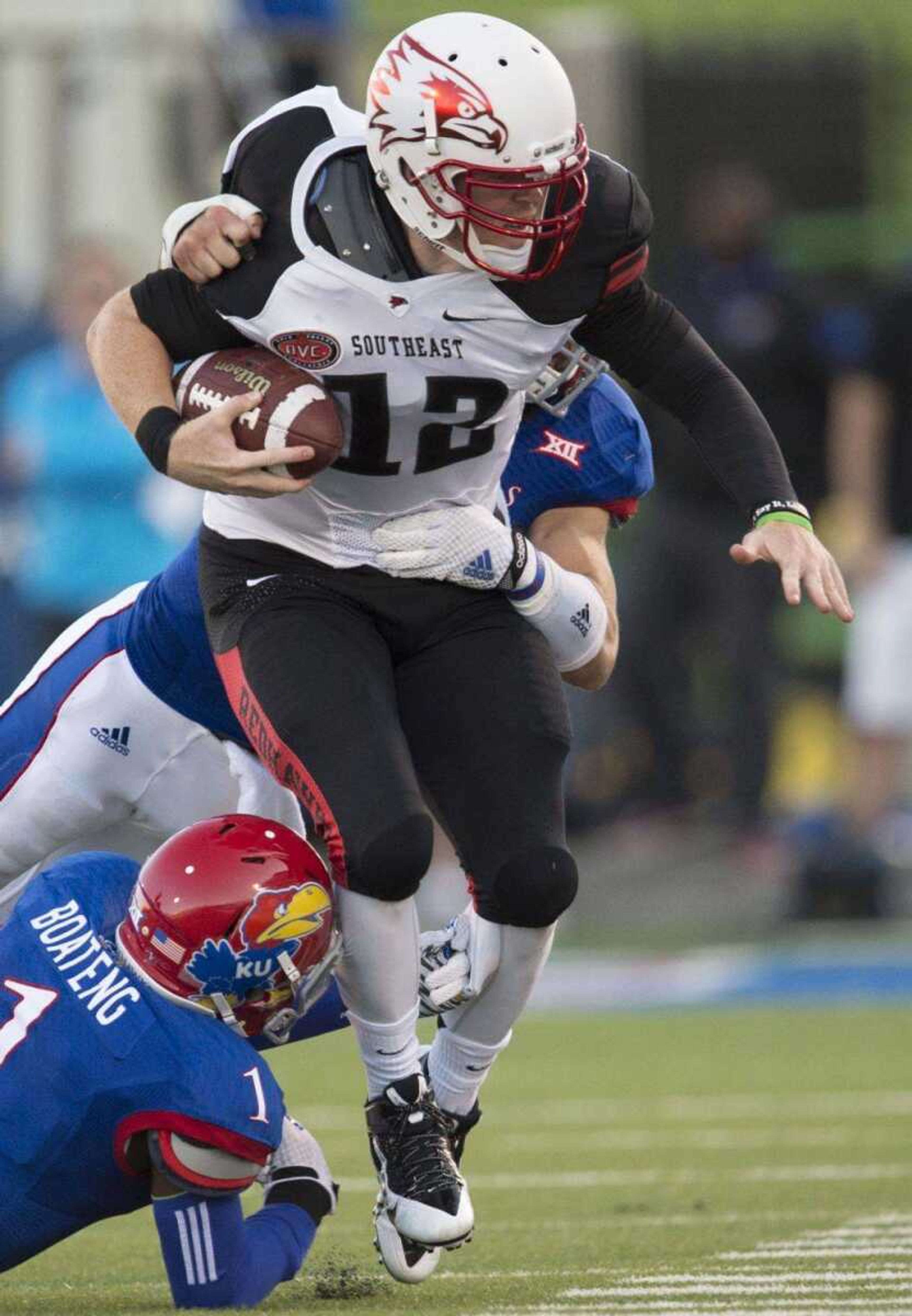 Southeast Missouri State Redhawks quarterback Kyle Snyder is hit by Jayhawks cornerback Matthew Boateng and linebacker Ben Heeney during the second quarter in Lawrence, Kansas.