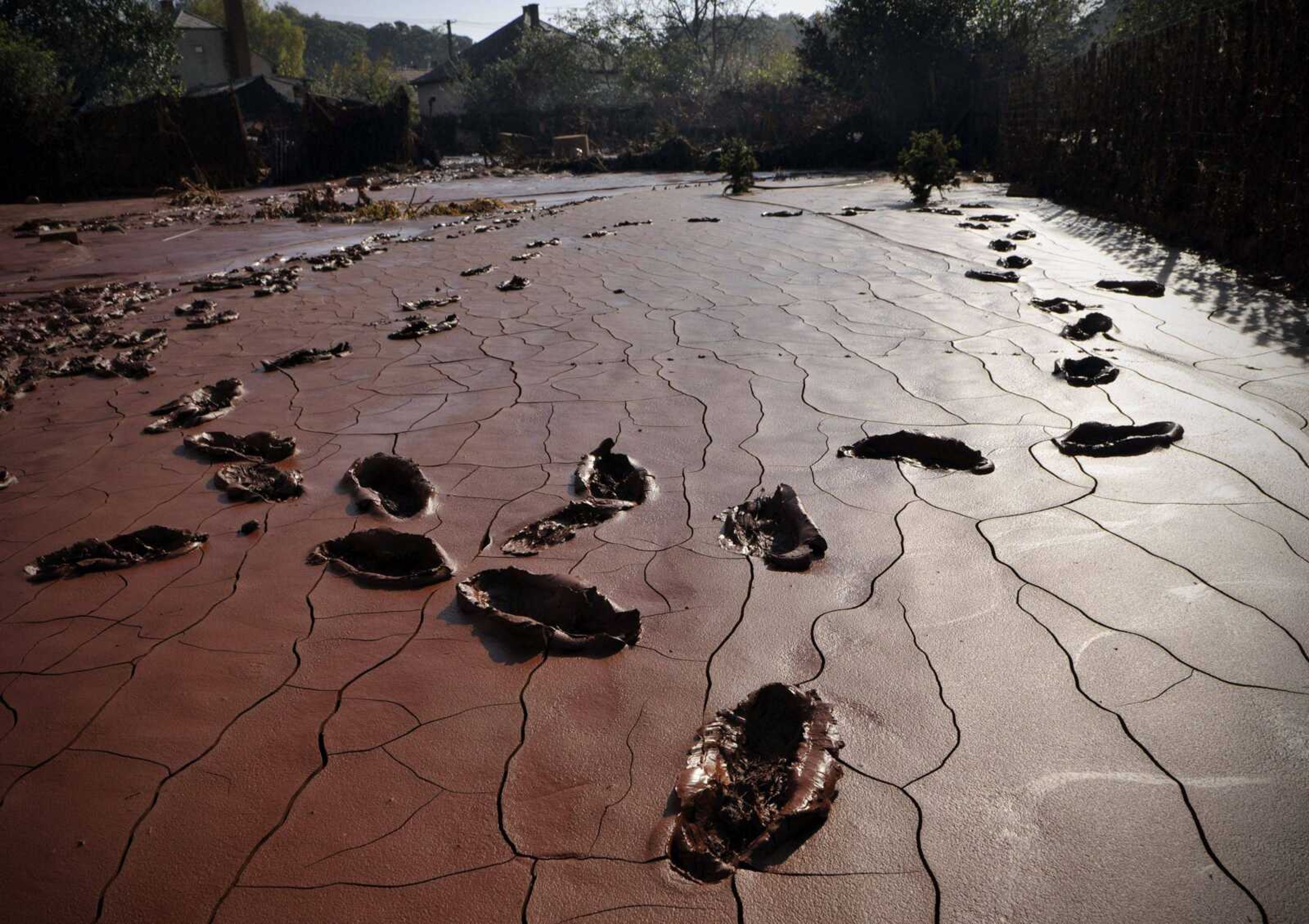 Footsteps pick their way through the toxic red sludge which covers a yard in Devecser, Hungary, Saturday, Oct. 9, 2010. The population of the neighboring town of Kolontar was evacuated early this morning, and Devecser with a population of 5,300 is also in the likely path of a new sludge deluge. Authorities asked residents to put their most essential belongings into a single bag and prepare for possible evacuation. (AP Photo/Bela Szandelszky)