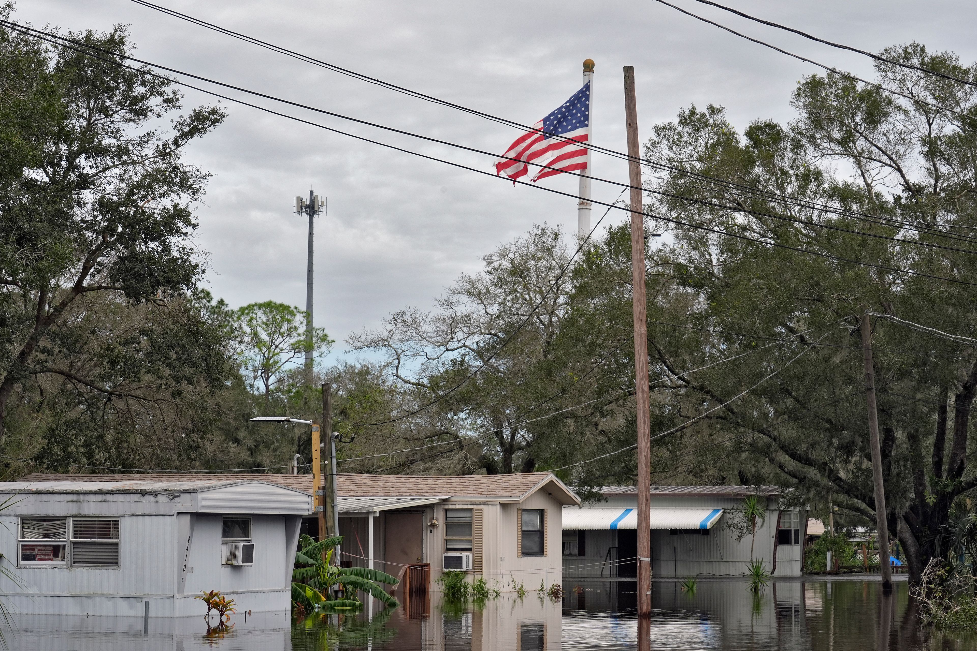 A tattered American flag flies above flooded homes, from Hurricane Milton along the Alafia river Friday, Oct. 11, 2024, in Lithia, Fla. (AP Photo/Chris O'Meara)