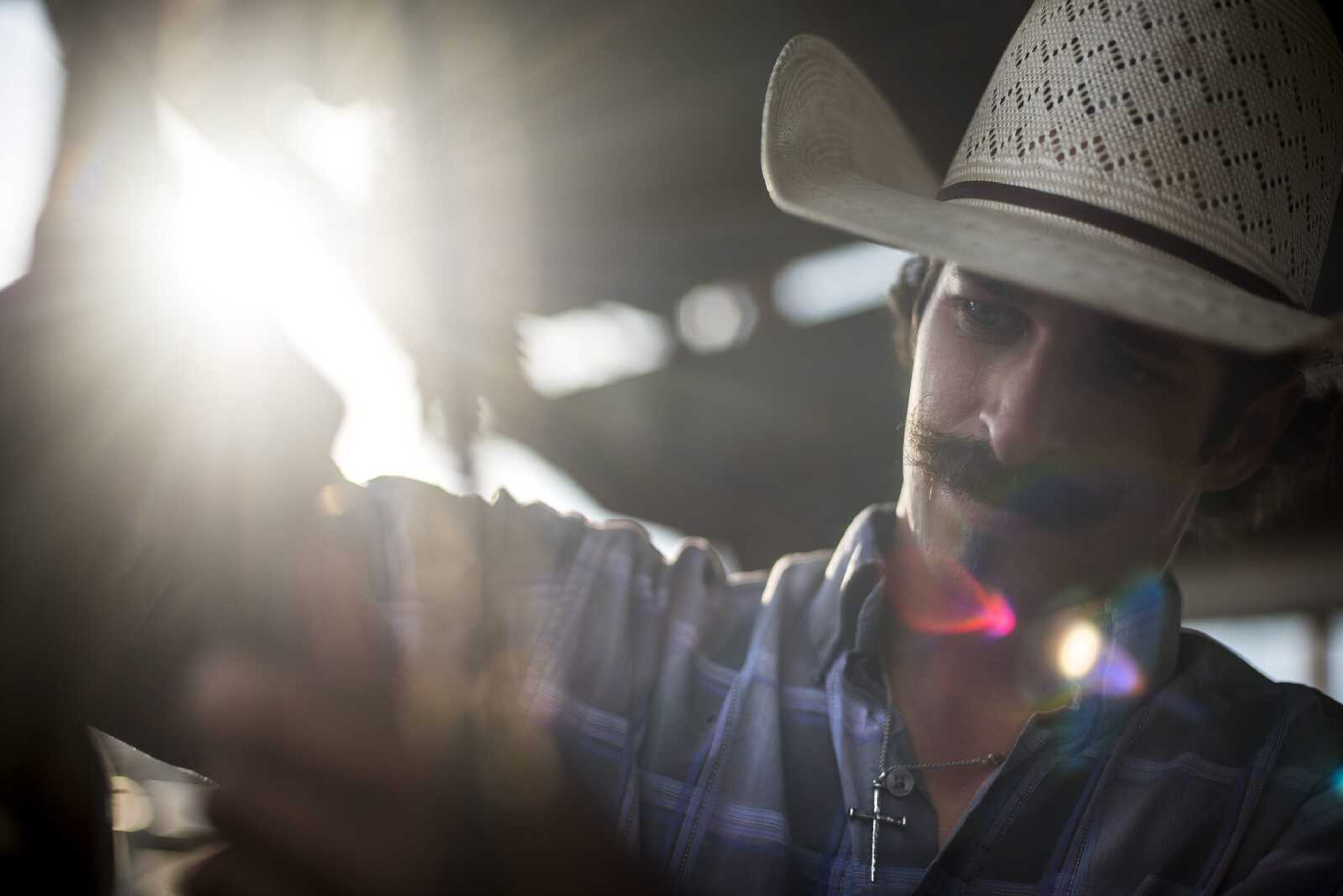 Travis Smith, of Thayer, Missouri, uses a knife to rough up the rosin on a strap while preparing to ride a bronco during the Sikeston Jaycee Bootheel Rodeo Wednesday, Aug. 7, 2019, in Sikeston.