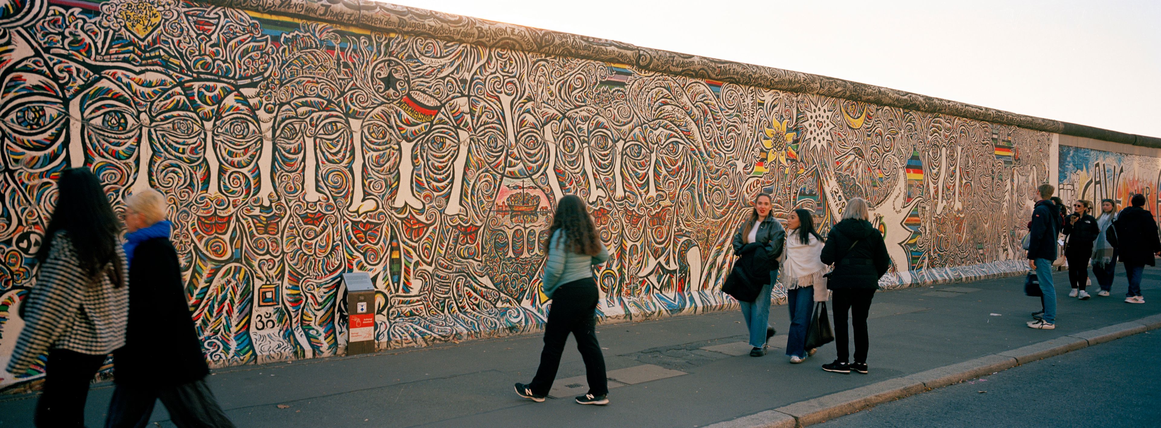 People gather at a painting at the so-called East Side Gallery, a popular place for street art on remains of the Berlin Wall in Berlin, Germany, Tuesday, Oct. 15, 2024. (AP Photo/Markus Schreiber)