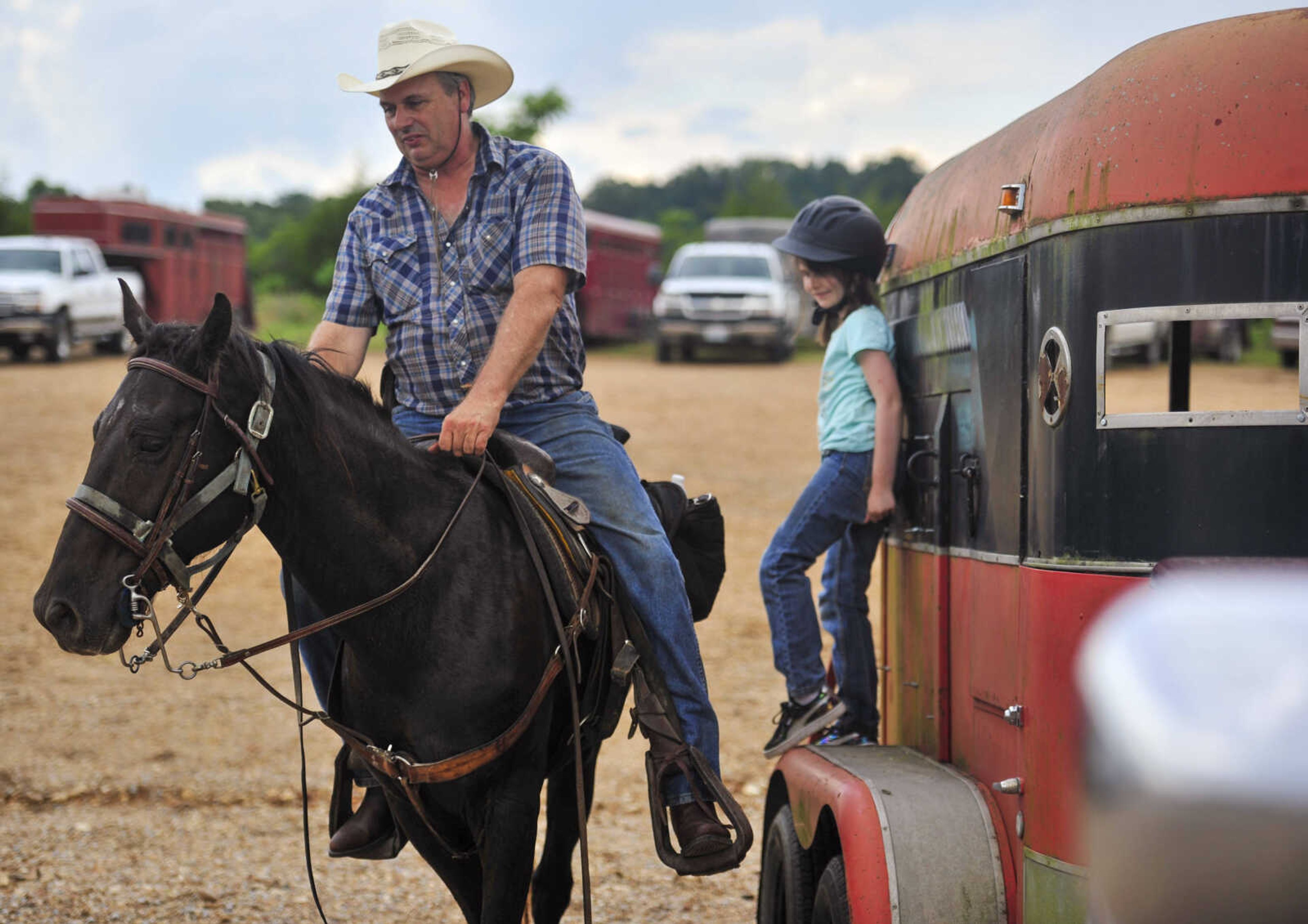 Addison Taylor, 8, right, leans against a horse trailer while her father, David Taylor, prepares to dismount after a trail ride sponsored by Jackson Trail Riders June 4, 2017, in Patton, Missouri.