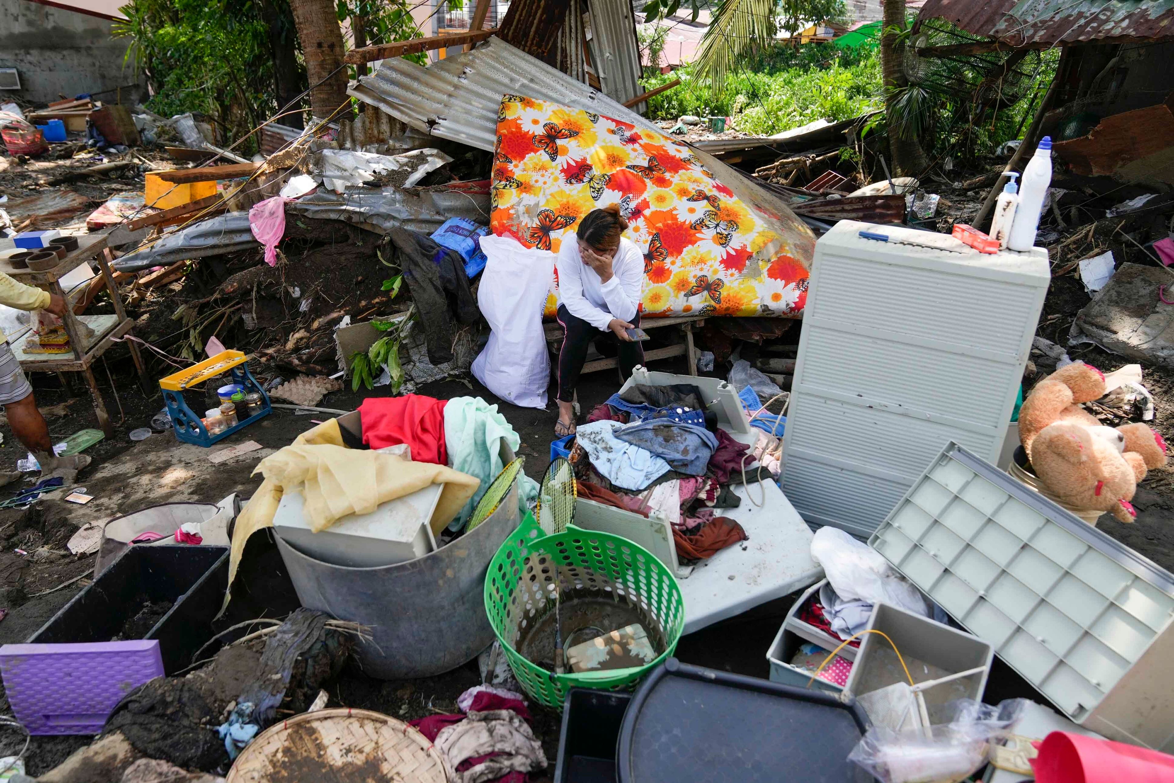 A resident sits beside belongings from their damaged home after a recent landslide triggered by Tropical Storm Trami struck Talisay, Batangas province, Philippines leaving thousands homeless and several villagers dead on Saturday, Oct. 26, 2024. (AP Photo/Aaron Favila)